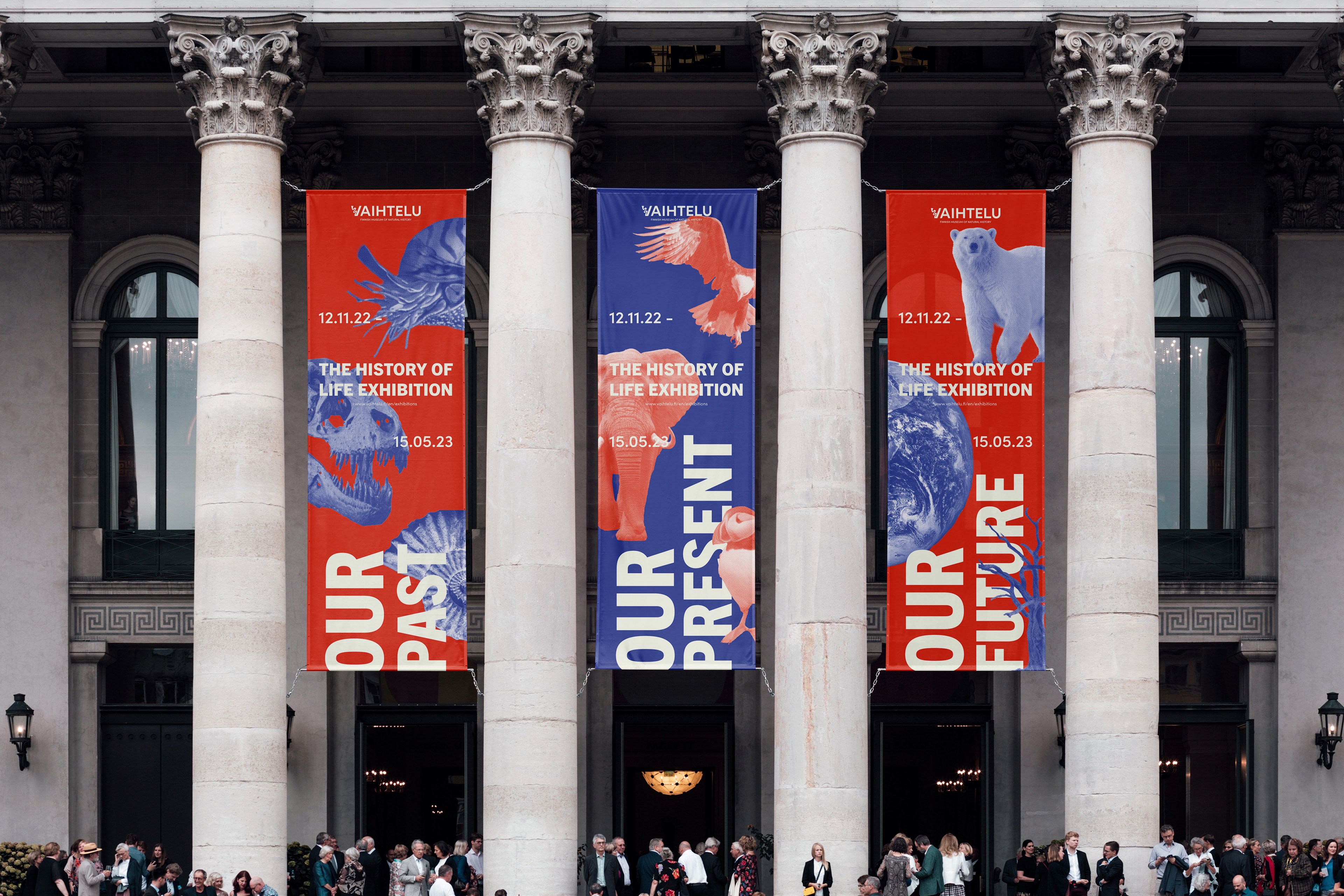 A set of 3 banners alternating red and blue in front of a museum advertising the History of Life Exhibition