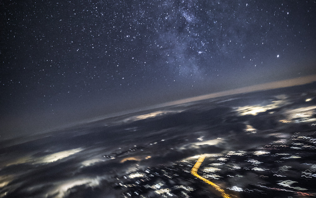 Milchstraße und Sterne über den Wolken aus dem Cockpit eines Verkehrsflugzeugs bei Nacht, Astrofotografie von Pilot Pascal Kamm auf über 11 000 Metern Höhe mit sichtbarem galaktischen Sternenband