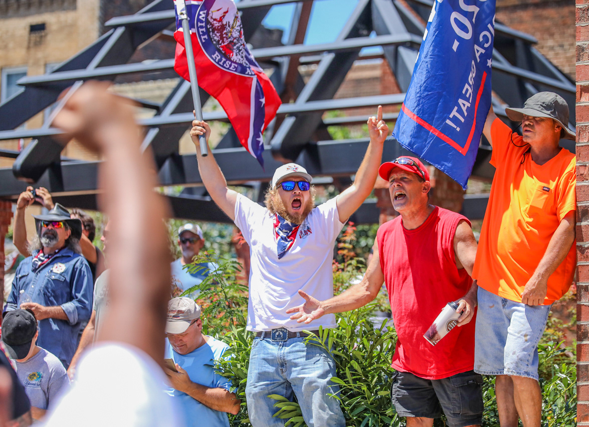 Counter-protesters wave "Trump 2020" and "The South Will Rise Again" flags.