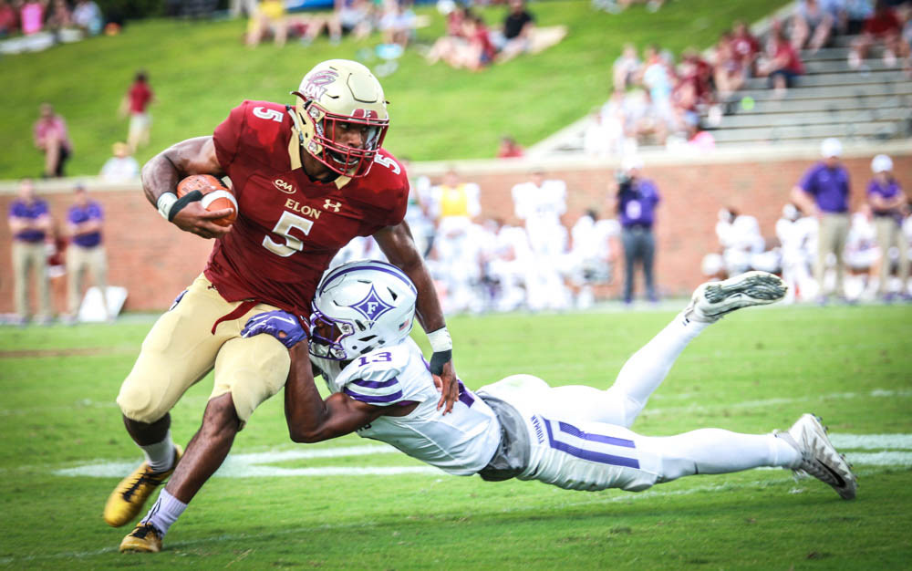 Elon runningback Malcolm Summers carries the ball past Furman cornerback Quandarius Weems during the first home football game of the season on Nov. 8, 2018. Summers rushed 78 yards during the game, scoring a 54-yard touchdown against the Furman defense. "It felt good to be up by a lot of points, " Summers said, after Elon defeated the Purple Paladins 45-7.