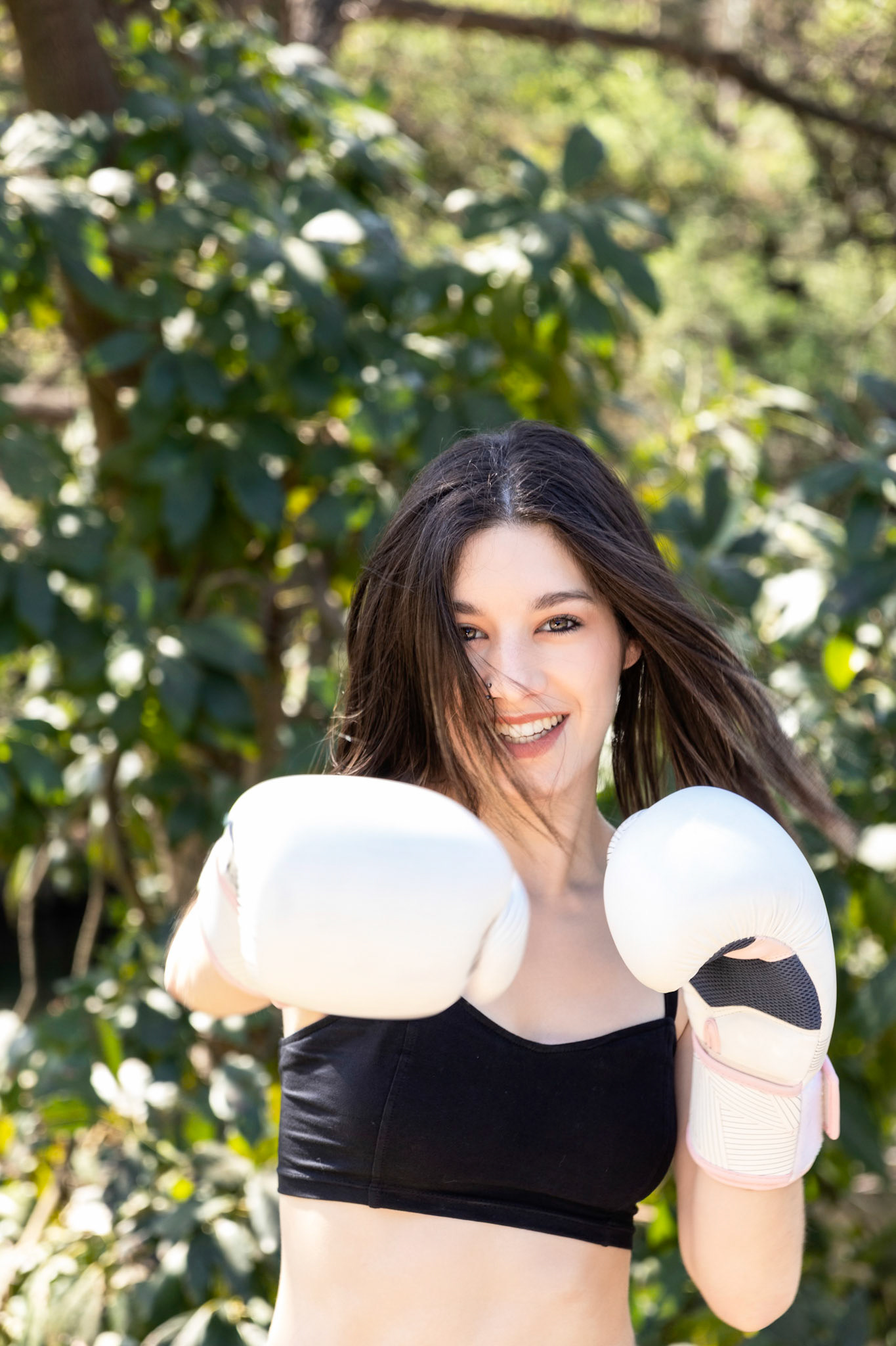 young female boxer with white gloves in a park