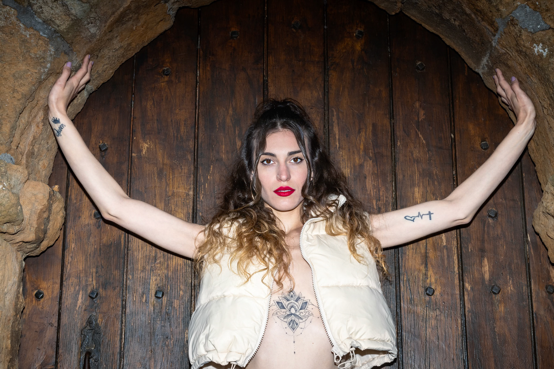 woman with tattoos standing against a wooden door