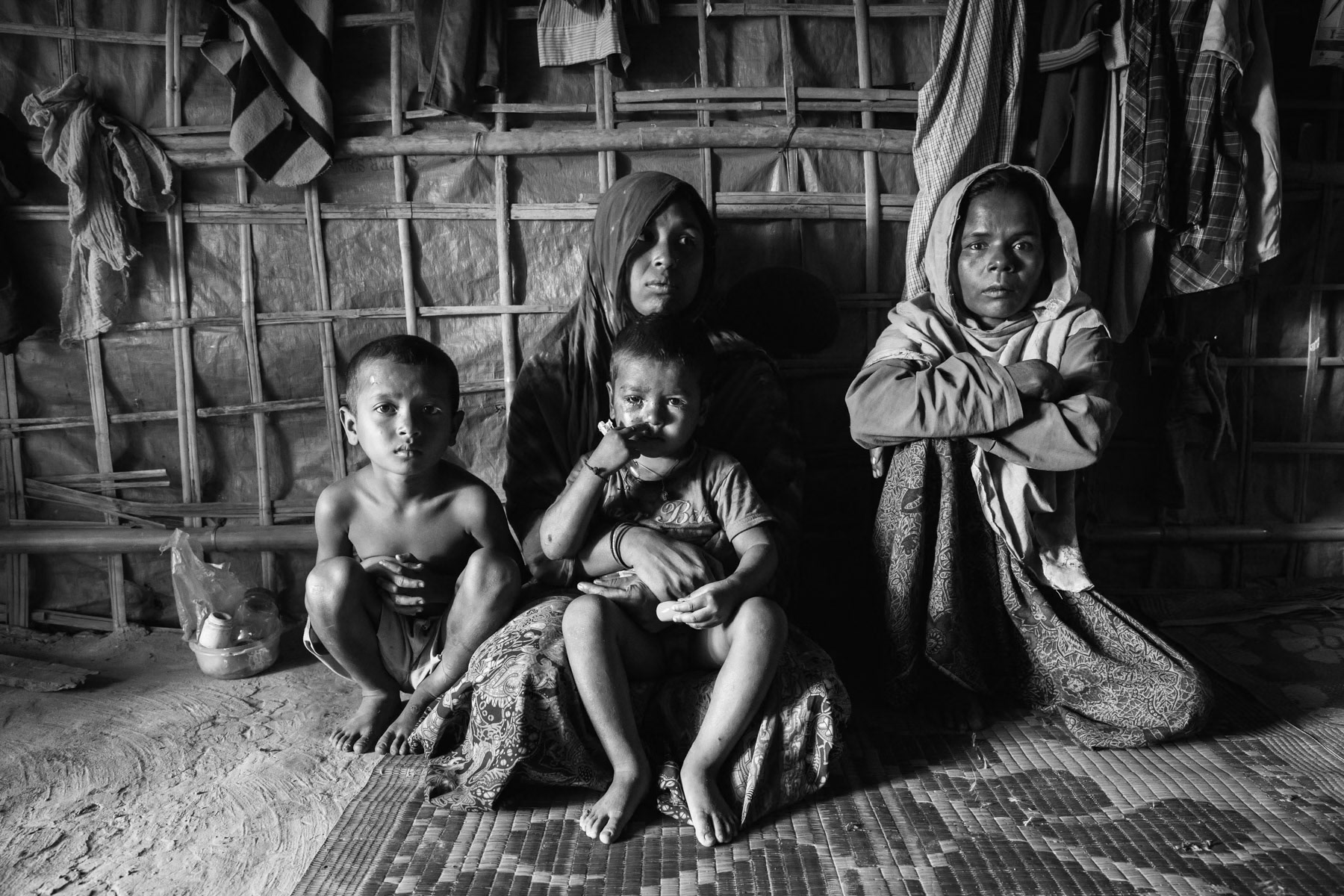 Subiya Khatun (left) and Nasima Khatun (right) from Chut Pyin near Rathedaung, Myanmar. Subiya is 35 years, her daughter of 15 was raped and consequently killed during the attack on their village by Myanmar military and local Rakhine mobs. Her husband was decapitated and 2 sons of 12 and 13 years were also killed in cold blood. She has one son who fled to Malaysia by boat in 2015 when he was 16 years. She hasn't received any phone call from him since March 2017 and has lost all track of him. Subiya is living with her 4 surviving young children in Bangladesh since Septamber 2017. Nasima is 37 years, her husband, her daughter of 12 and two sons of 18 and 19 were massacred by the military during the attack on the village in August 2017. In Myanmar they were farmers owning considerable large plots of land. Nasima survives now in the refugee camps with her 5 remaining children, the youngest one being born few weeks before the attack. Thangkhali Rohingya refugee camp in Bangladesh, October 2018