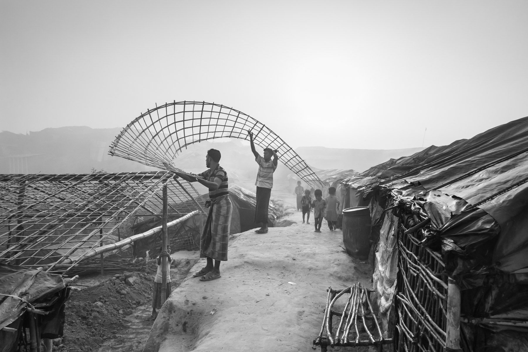 A Rohingya family building their makeshift shelter with donated materials. The huge influx of refugees during the past months has put an enourmeous strain on the local environment and economy resulting in substantial deforestation, pollution, price hikes and tensions with local communities. Thangkhali refugee camp, Ukhiya, Bangladesh, March 2018
