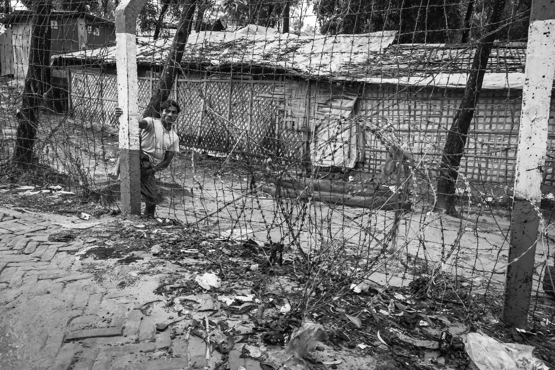 Rohingya refugee from Myanmar exiting a refugee camp. All the refugee camps for Rohingya have been sealed off with barbed wire fences and became de-facto like open-air prisons. Movements in and out the refugee camp area is heavily restricted. More than one million Rohingya refugees live in the camps with no perspective of return to their homeland or re-settlement in a third country. Kutupalong refugee camp, Ukhiya, Cox's Bazar, Bangladesh, September 2022