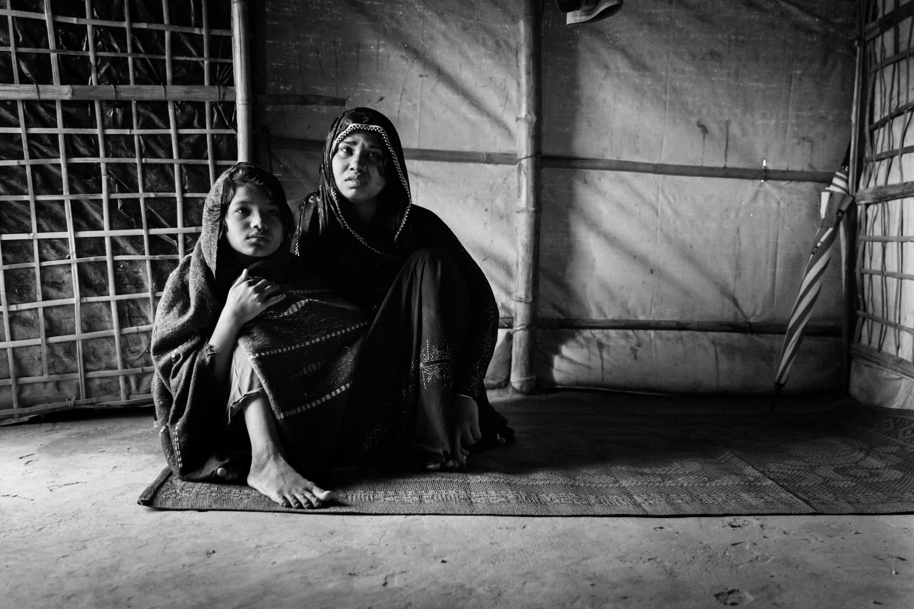 Dildar Begum, 30, and her daughter Nur Kolima, 10, from Tula Toli in Maungdaw township. Her entire family was massacred (decapitated) in fromt of her. Her husband, 2 sons, and one daughter. She and her daughter Nur are the sole survivors. She was gang raped at her house by military and local rakhine. Her surviving daughter, Nur, has been assaulted with a machette and left for dead. After being raped Dildar was also assualted by machette and left for dead, their house with all corpses were set on fire. She managed to escapre through the back with Nur. They fled alone for 5 days through the jungle both badly injured and losing a lot of blood. Having no food, they were feeding themselves with leaves. They finally reached Bangladesh and were transferred to Chittagong hospital where they had blood transfusions. They have been in the refugee camps since October 2017. Her daughter Nur has recognized one of the assaillants as A.S. (Aung Shingha), a Rakhine of a neighbouring village. Nur goes nowadays to school in the camps where she learns English, Burmese and mathematics. Hakimpare camp for Rohingya refugees, Bangladesh, October 2018