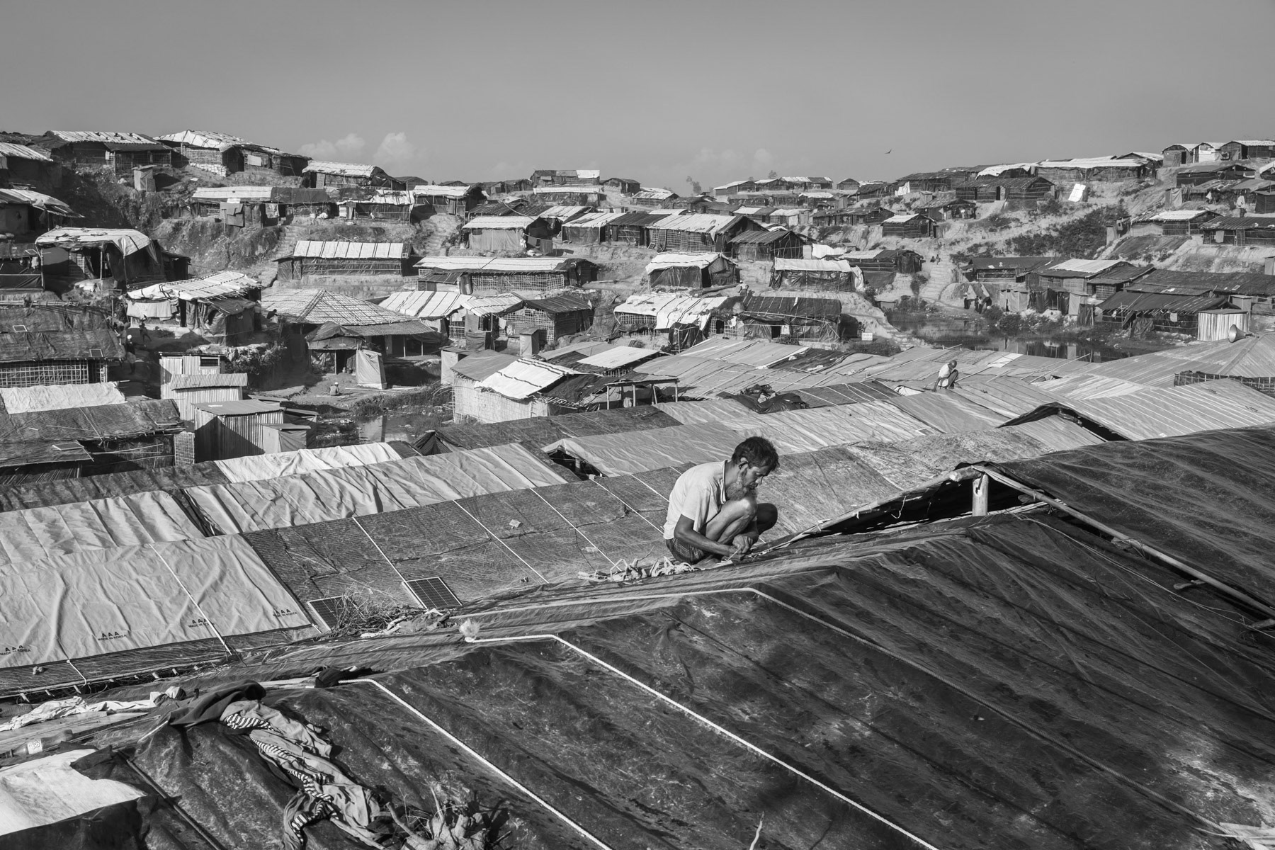 Fixing the roofing at new makeshift blocks for newly arrived Rohingya refugees from Myanmar. More than 650,000 refugees have fled persecution and brutal ethnic cleansing in neighbouring Myanmar since August 2017. Balukhali refugee camp, Ukhiya, Bangladesh, November 2017