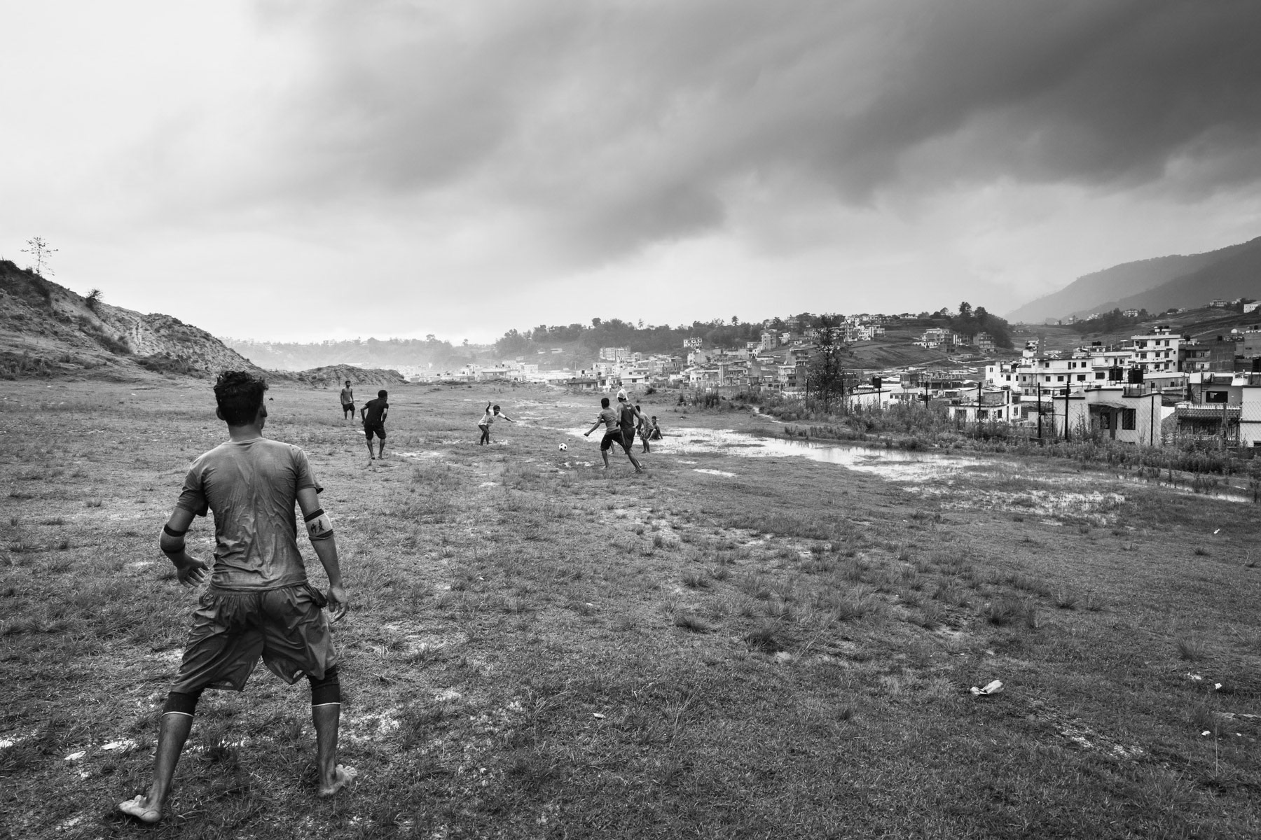 Rohingya refugees from Myanmar playing football at the beginning of the monsoon season. Kathmandu Valley, Nepal, July 2017