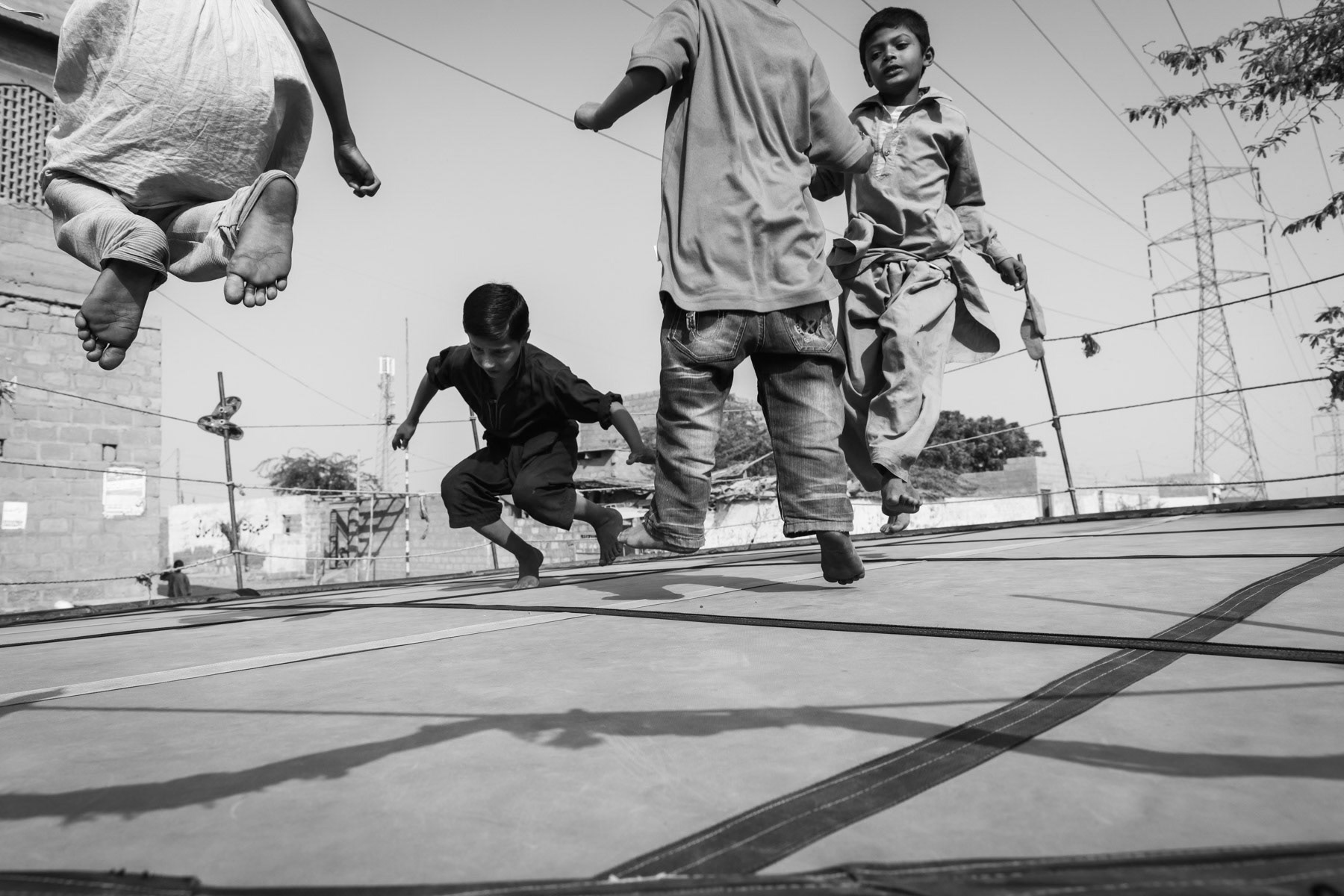 Rohingya children playing on an outdoor trampoline. Hundred Quarters in Korangi suburb of Karachi, Pakistan, December 2016