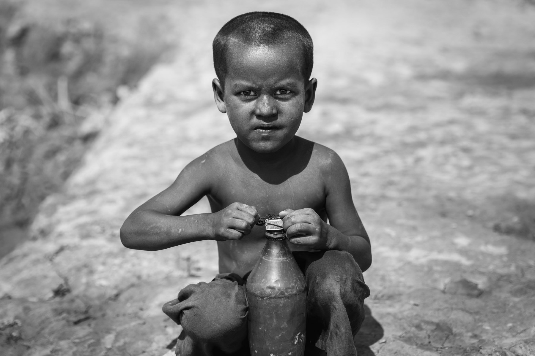 A Rohingya boy near the pond collecting the little water remaining, Kyin Ni Pyin IDP Camp, Rakhine, Myanmar, May 2017