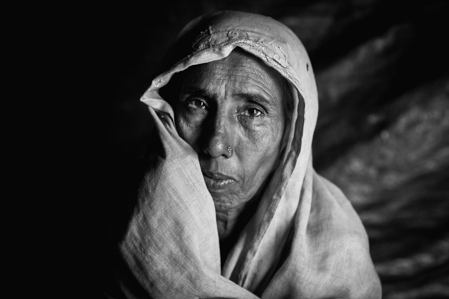 Nurashah Khatun, 60 years old Rohingya refugee from Maungdaw township in Myanmar. Her village was attacked in August 2017, she reached Bangladesh after 2 days walking. She lost track of her husband and 17 year old daughter, they have been missing ever since. She lives in Balukhali refugee camp with her 4 surviving daughters ever since. Human rights organisations have stated that thousands of Rohingya have been killed and missing ever since the military operations in Northern. Thousands of girls and women have been tortured and systematically raped in a situation that has evolved from ethnic cleansing to genocide. Balukhali camp for Rohingya refugees, Bangladesh, October 2018