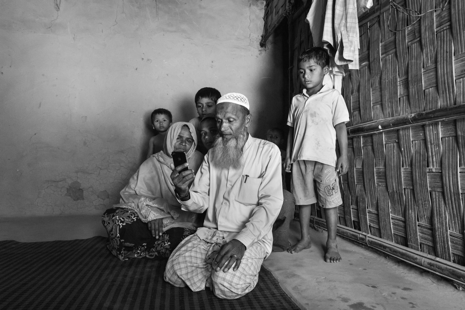 Family communicating with their son Zahid in Malaysia for the first time since they fled Myanmar. Zahid fled to Malaysia by boat as a refugee in 2009 and is now providing money for his family. The family arrived two weeks earlier to Bangladesh and lives in a shed they rent for 40 dollar per month. Nhila village, Teknaf, Bangladesh, February 2017