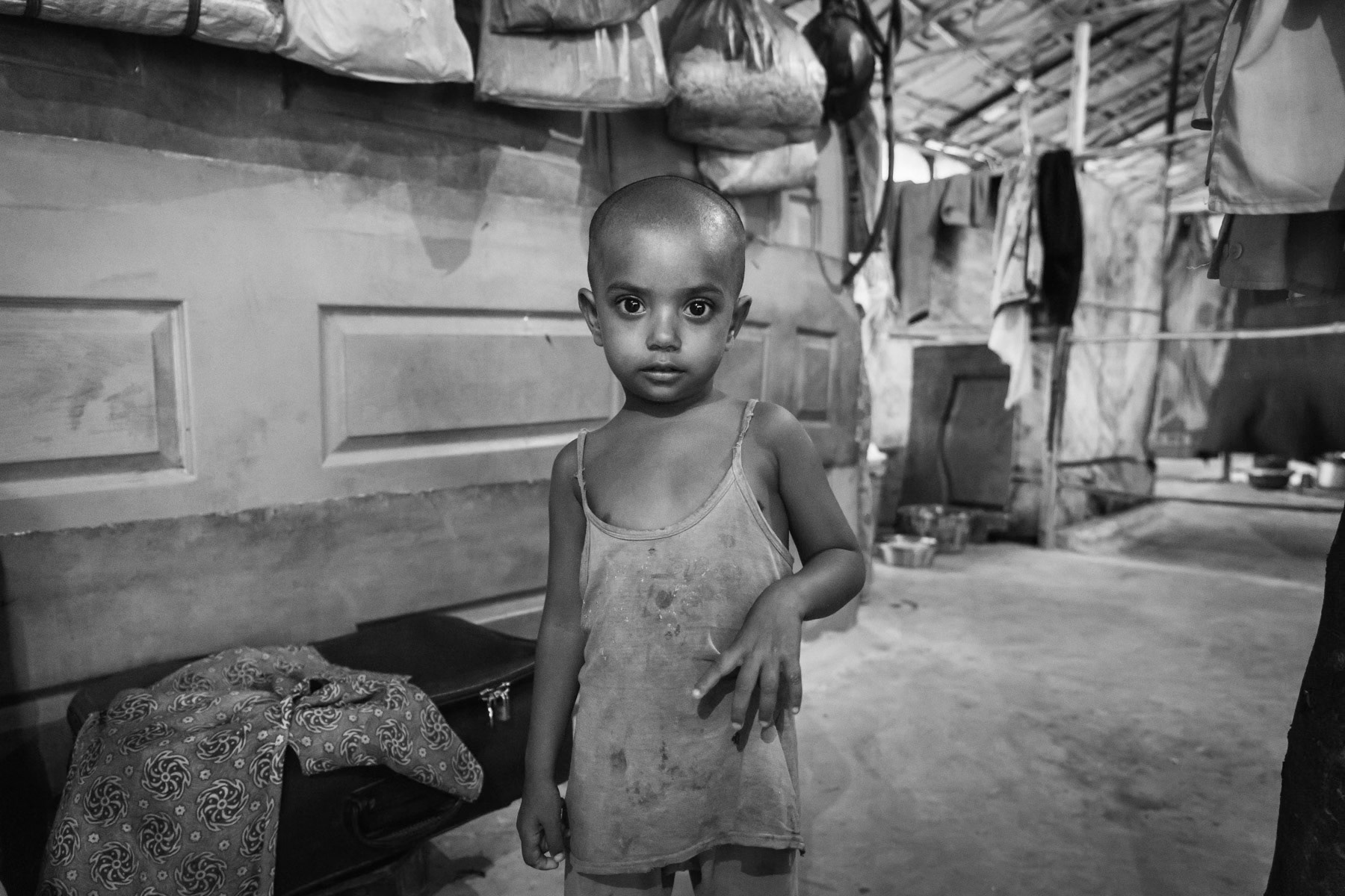 Child in a makeshift shelter hosting up to 8 families, Balapur camp, Hyderabad, India, June 2016