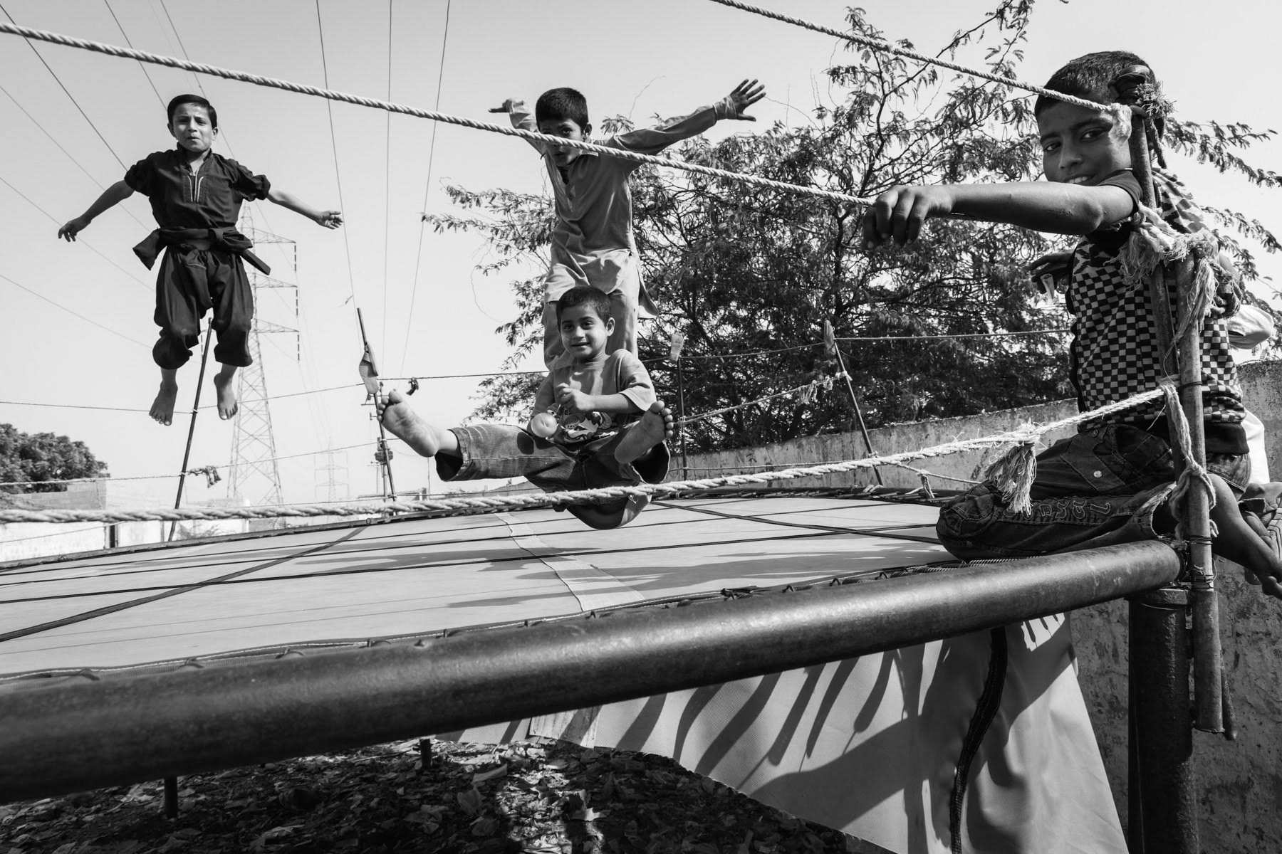 Rohingya children playing on an outdoor trampoline. Hundred Quarters in Korangi suburb of Karachi, Pakistan, December 2016