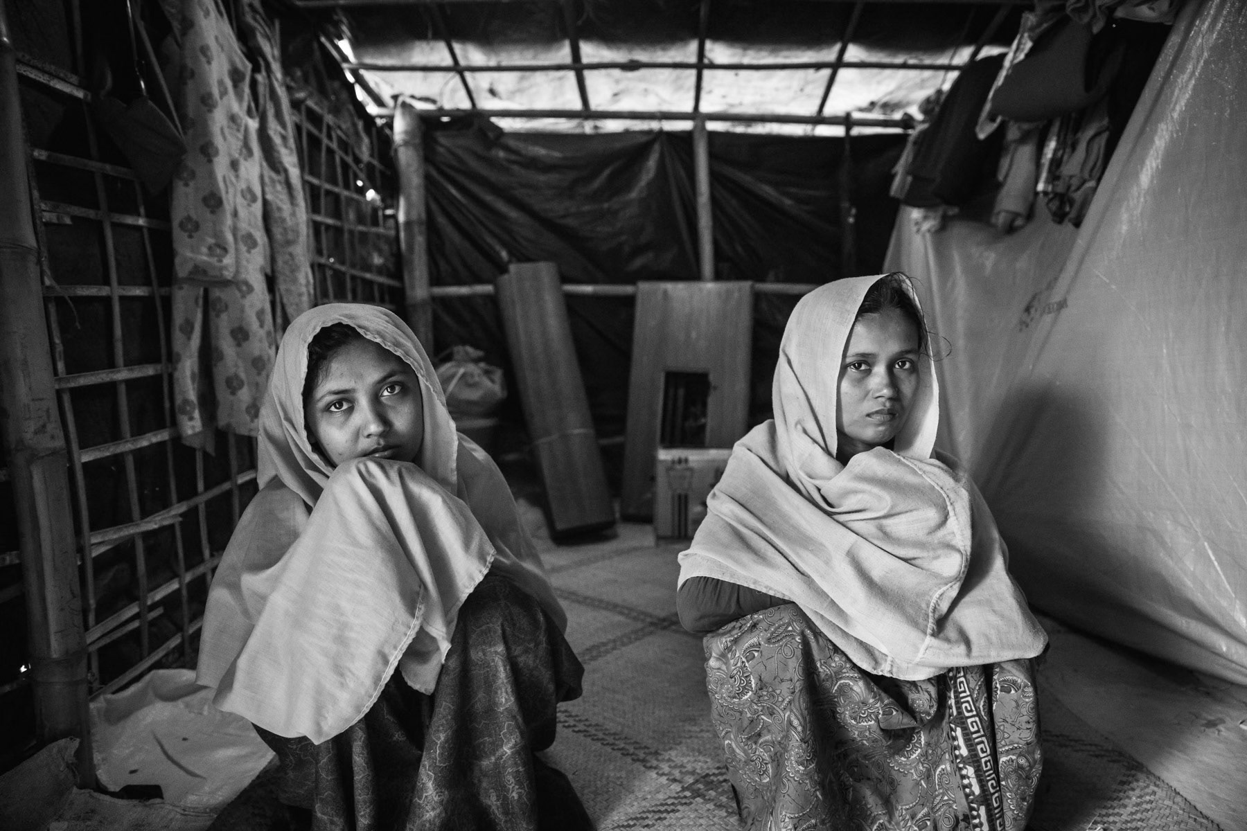 Two sisiters, Shopika Begum (left), 20 years and Rashida Begum (right), 25 years, from Tula Tuli in Maungdaw township in Myanmar. Both were gang raped by the Burmese military forces that attacked the village on 30 August 2017. Shopika's husband was executed and decapitated, Rashida's husband managed to escape, but her two children were executed. The two sisters were taken with approximately 30 other women to separate barracks where they would be repeatedly gang raped by groups of 5-6 military. After the gang rapes the women would be assaulted with machette, left for dead and burned inside the barracks. Very few survived, only those that had still the strenght to escape through the back and the fields. It took them both 5 days to reach Bangladesh using seperate routes. They were reunited once in Bangladesh. There have been countless testimonies of atrocities carried out by the Burmese regime and its military forces. Human rights commissions and international groups have called the ongoing onslaught a schoolbook example of ethnic cleansing evolving into a genocide of the Rohingya community in Rakhine. Widespread gang rapes have been widely documented through testimonies of the survivors in the camps. Balukhali camp for Rohingya refugees in Bangladesh, November 2017