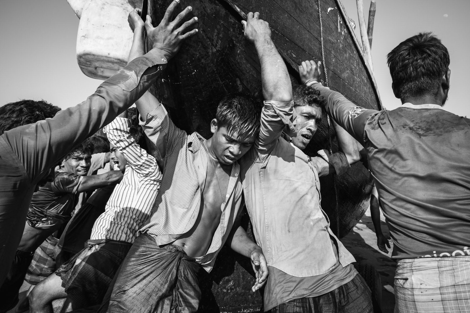 Rohingya daily labour pushing the fishing boat onto the beach after several days at sea. The boat owners are local and cash-in the bulk of the money made. Daily labour make between 1 and 3 dollar a day, sometimes less. Shamlapur near Teknaf, Bangladesh, February 2017