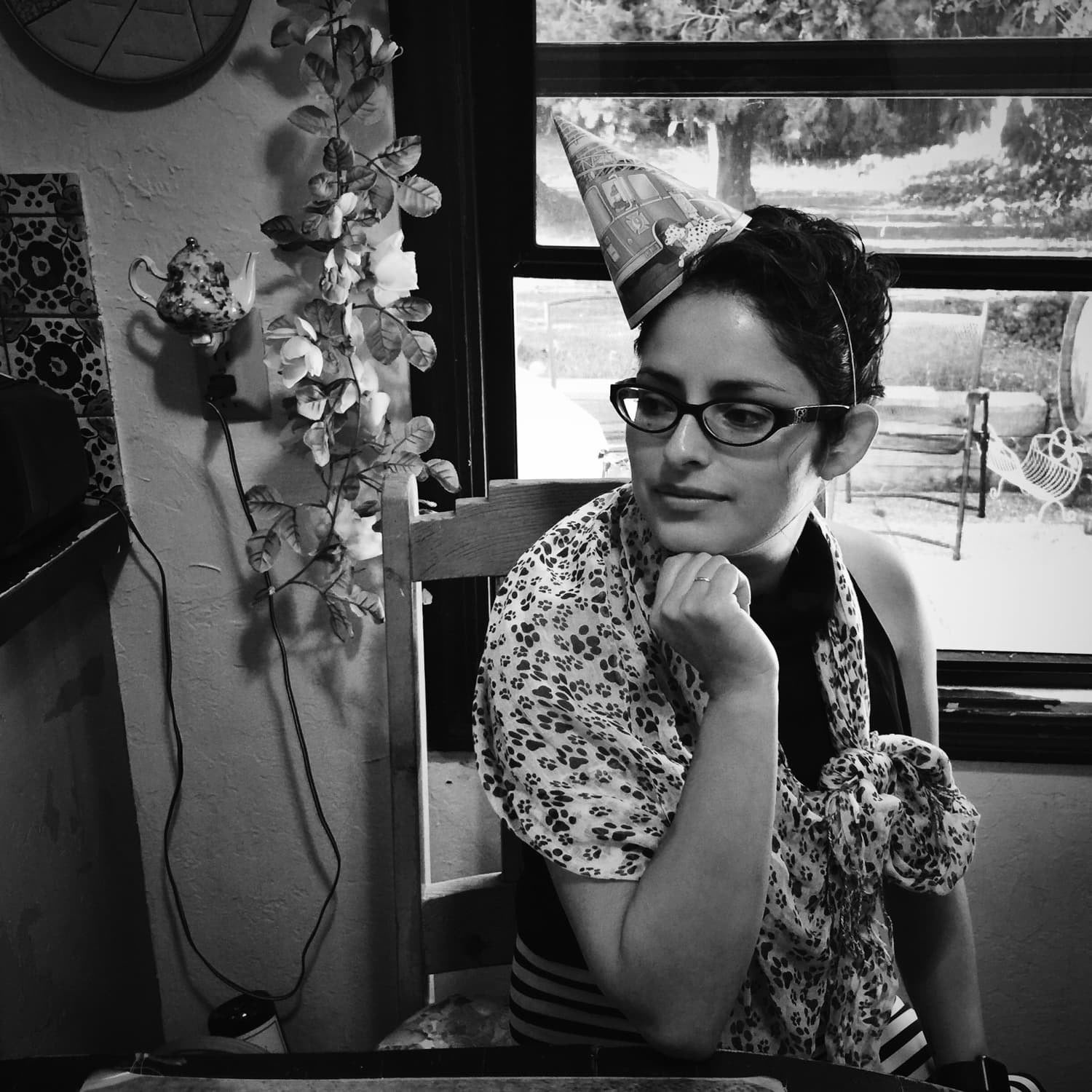 Girl in party hat sitting by window