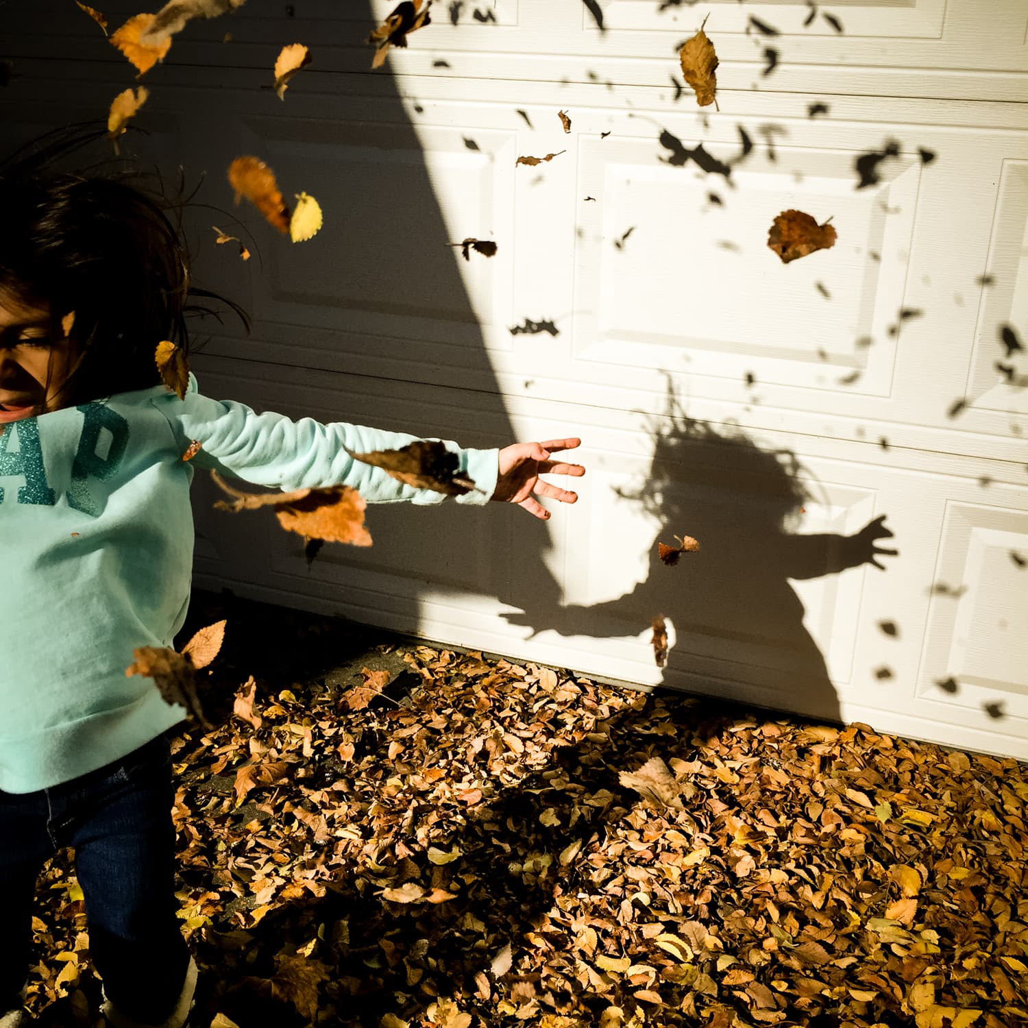 Child playing with leaves in the fall