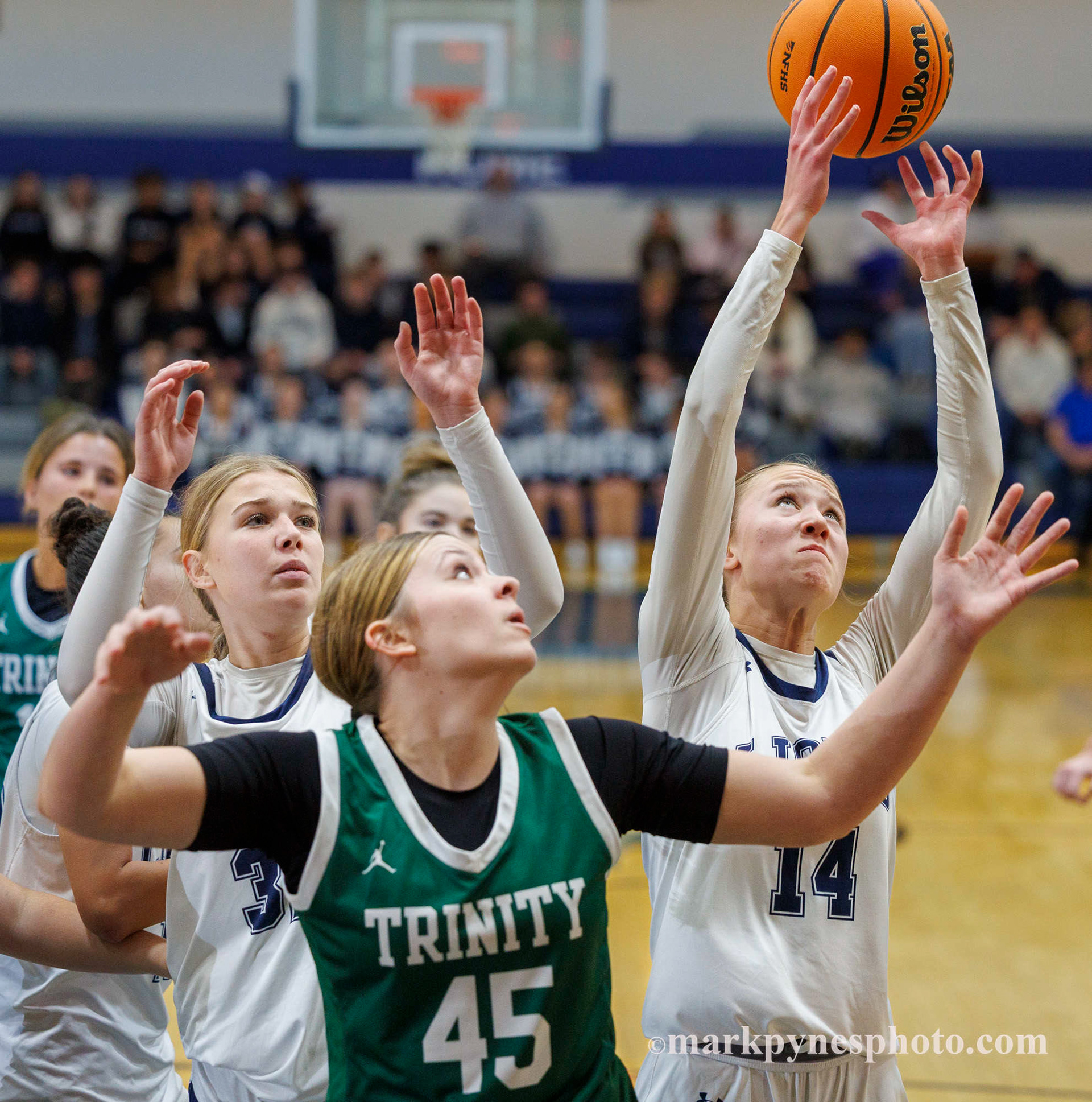 Camden Werley grabs a rebound behind Trinity’s Lillian Kertis, but Trinity wins.