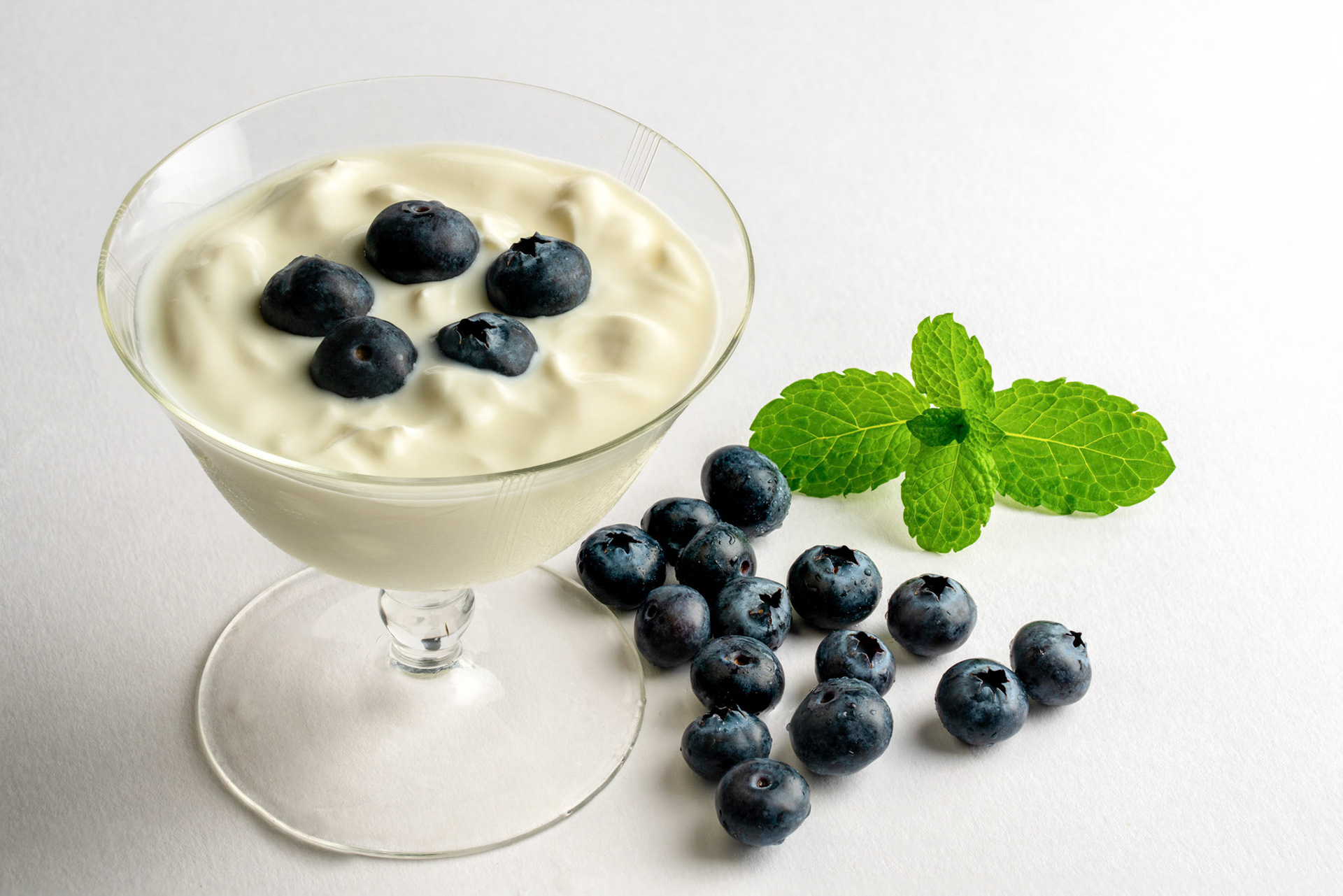 Blueberry and yoghurt desert in a fine glass dish on a white background.