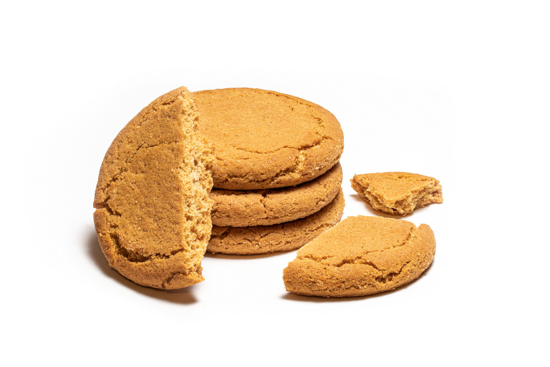A stack of crunchy ginger biscuits with one of them broken into three pieces