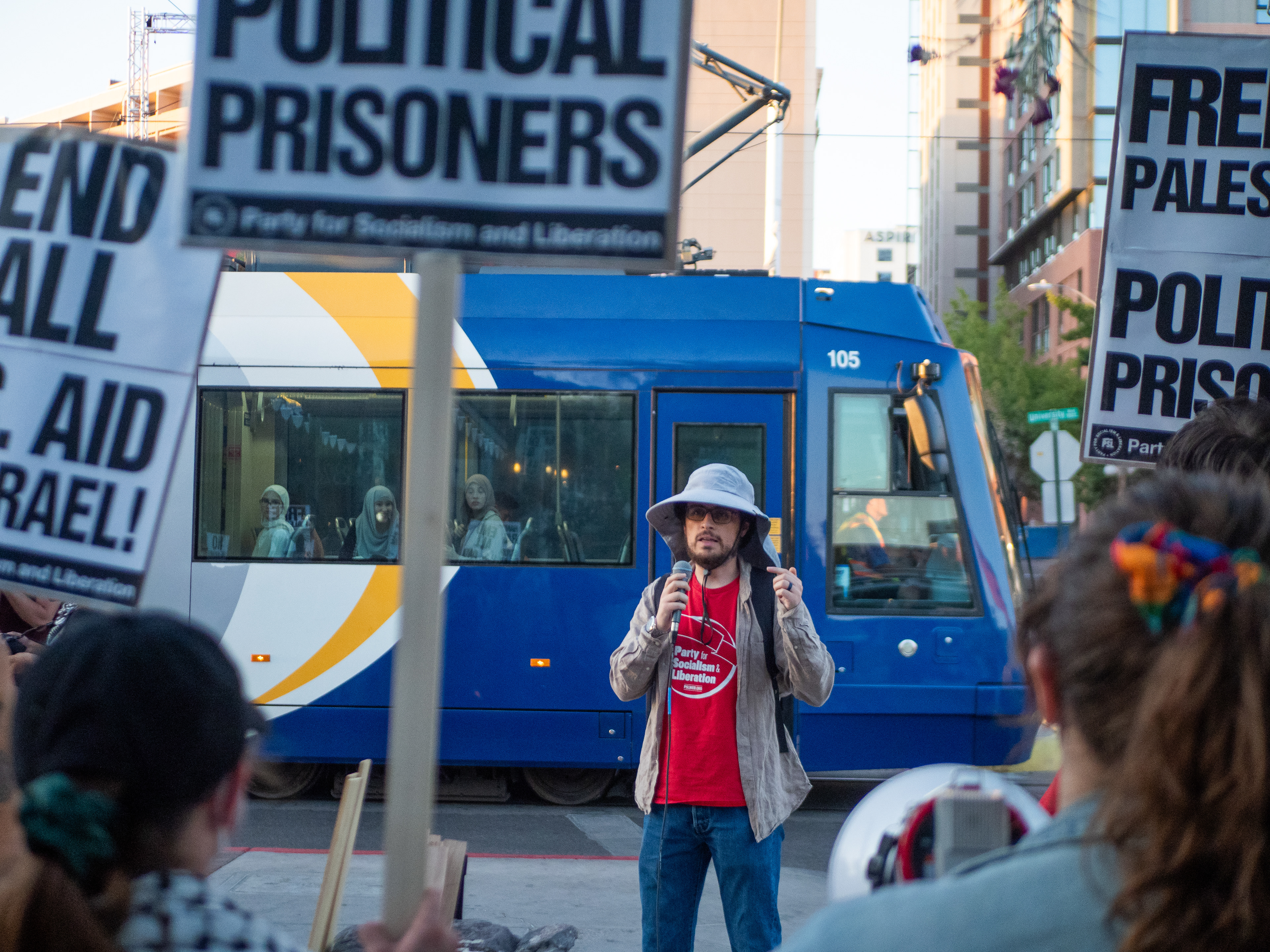 A speaker talking at the All out for Lebanon protest at the Main Gate in Tucson Arizona on September 24. Multiple streetcars passed while the protestors talked to the public and their group.