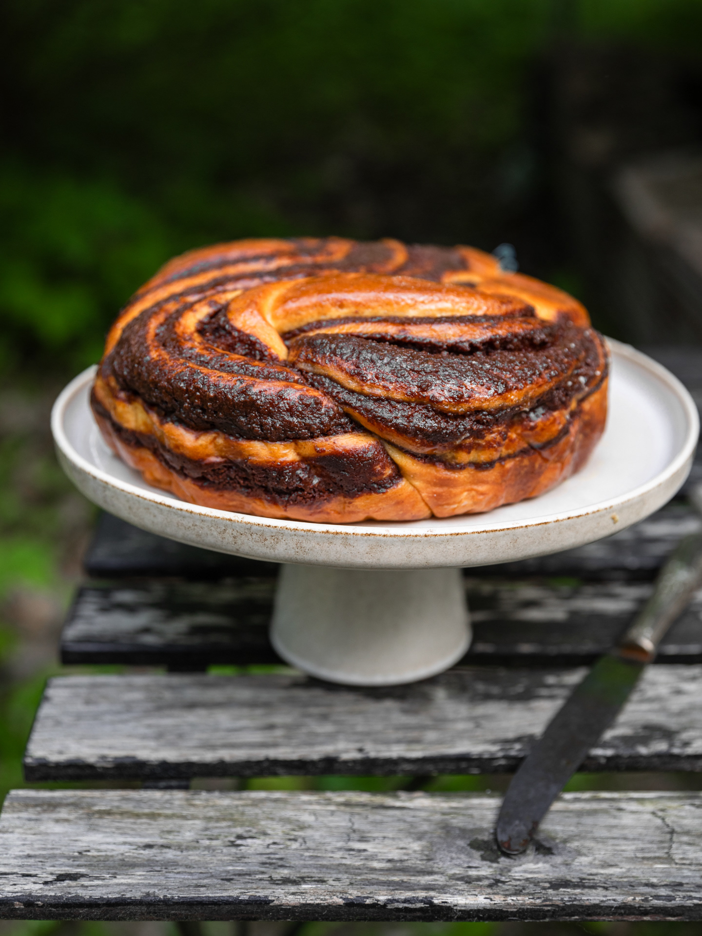 A food image of a babka dessert served of a cake stand and captured outdoors by Ioana Ursu Photographer and Stylist based in Warwickshire, West Midlands UK