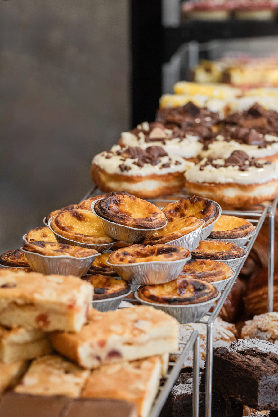 A restaurant photography and hospitality image made for a local bakery showcasing the freshly baked products at the counter like donuts, pastel de nata, brownies and other sweets made by Ioana Ursu restaurant and hospitality photographer based in Warwickshire