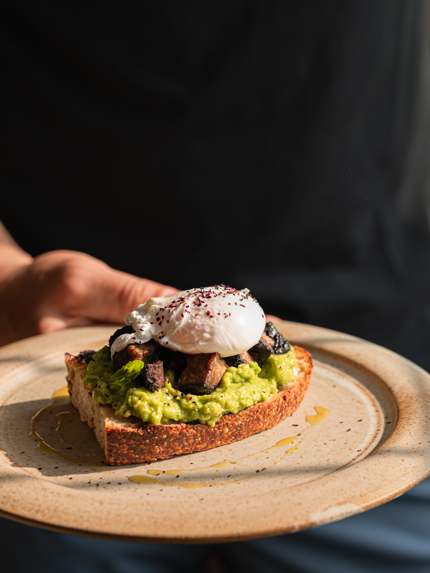 A food photography image of a poached egg on toast served with avocado and mushrooms on a plate, captured by Ioana Ursu Restaurant Photographer based in West Midlands