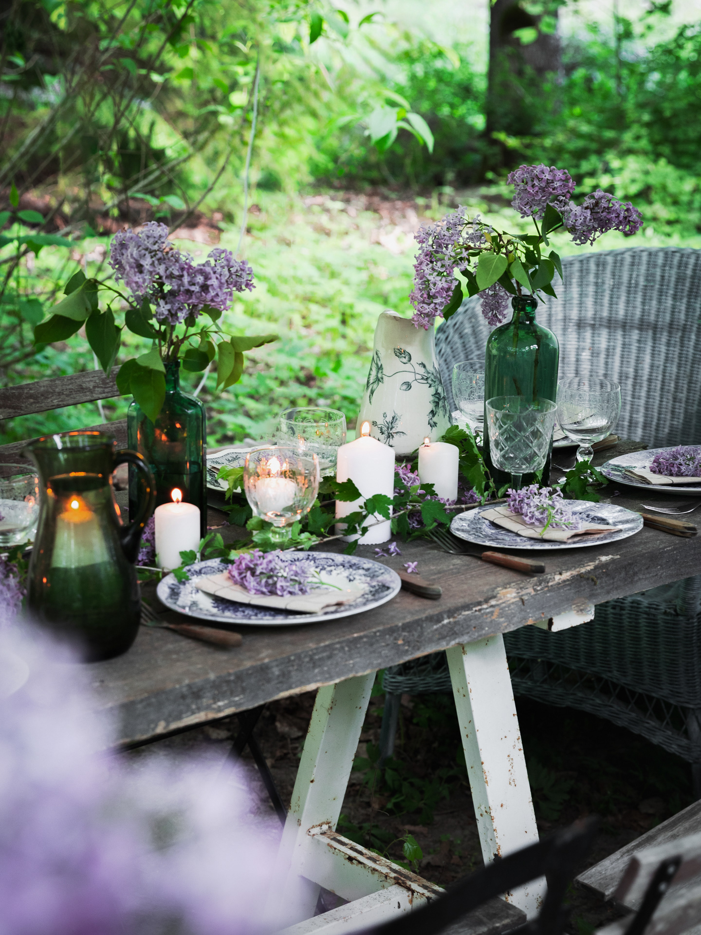 An outdoor scene image of a table prepared for serving food outdoor, decorated with candles, plates and flours made by Ioana Ursu Food and Lifestyle Photographer Warwickshire UK