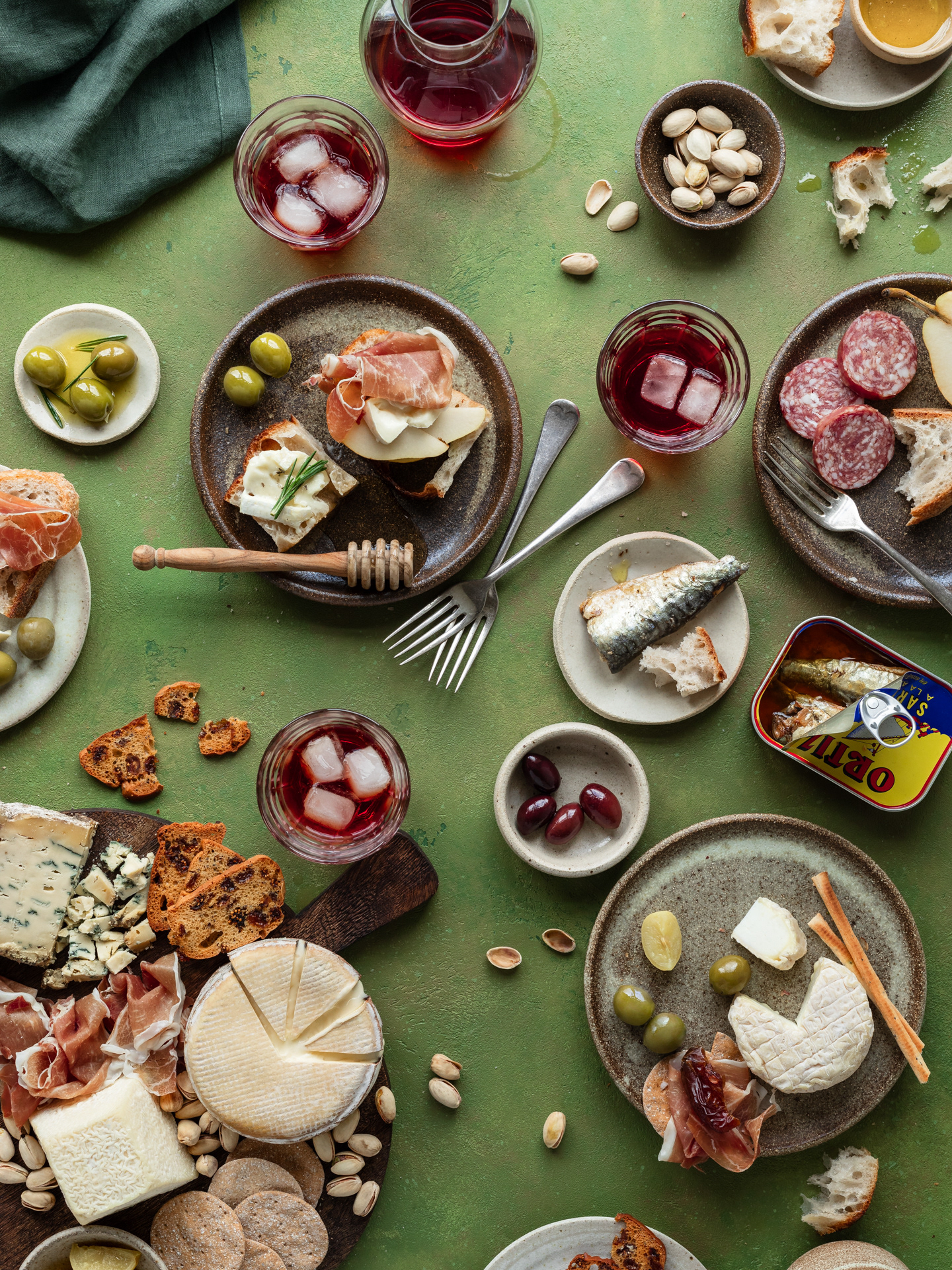 An aperitivo style image with many plates and servings such as olives, bread, sardines, olive oil, focaccia and drinks made by Ioana Ursu Food Photographer