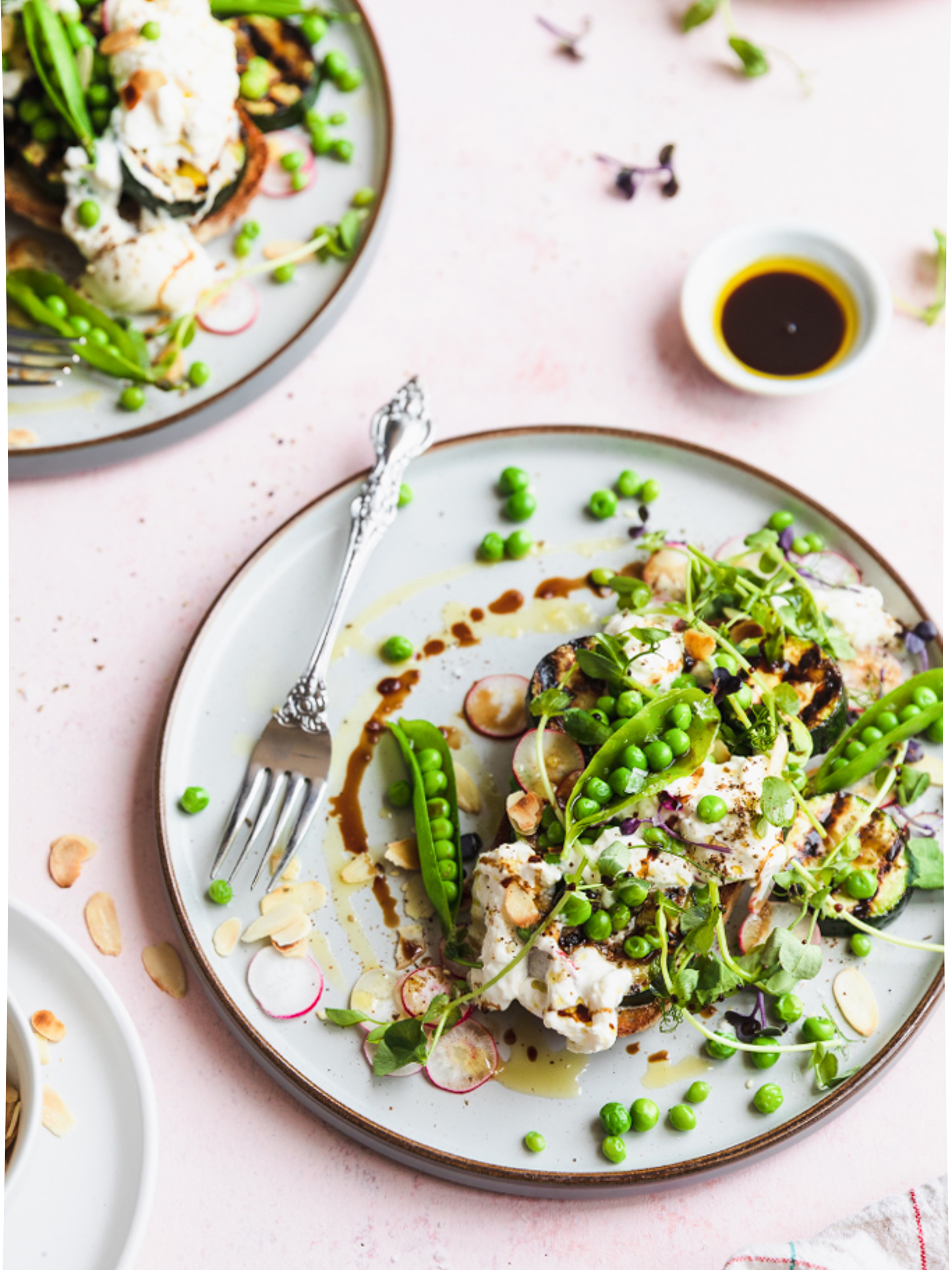 A food styling portfolio image of burrata and peas bruschetta served on plates, food styling and photography by Ioana Ursu