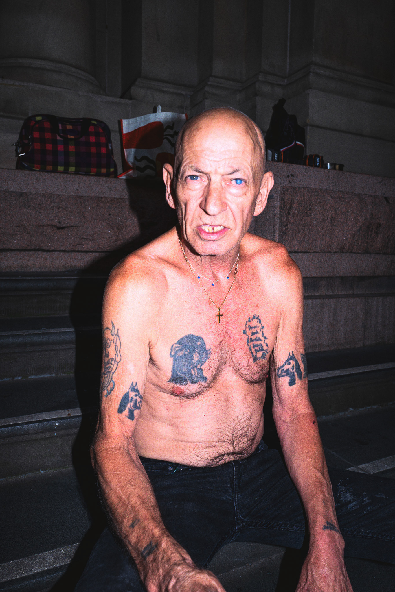 Tattooed man sitting on steps of H&M building in Melbourne