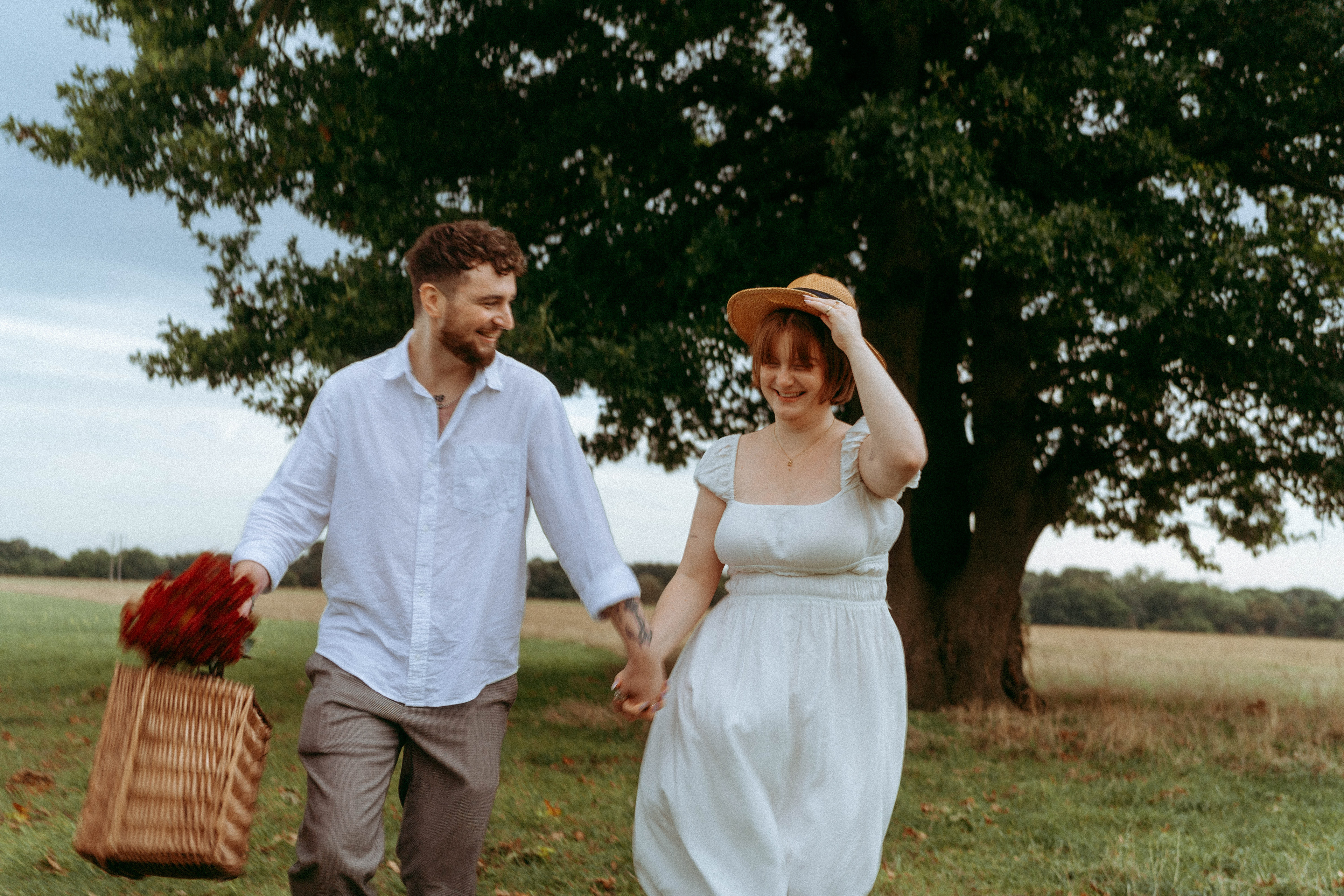 An intimate and playful engagement story set against a grand oak tree. A blend of romantic lifestyle photography and high-end editorial portraits, featuring a curated picnic setting in the Essex countryside.