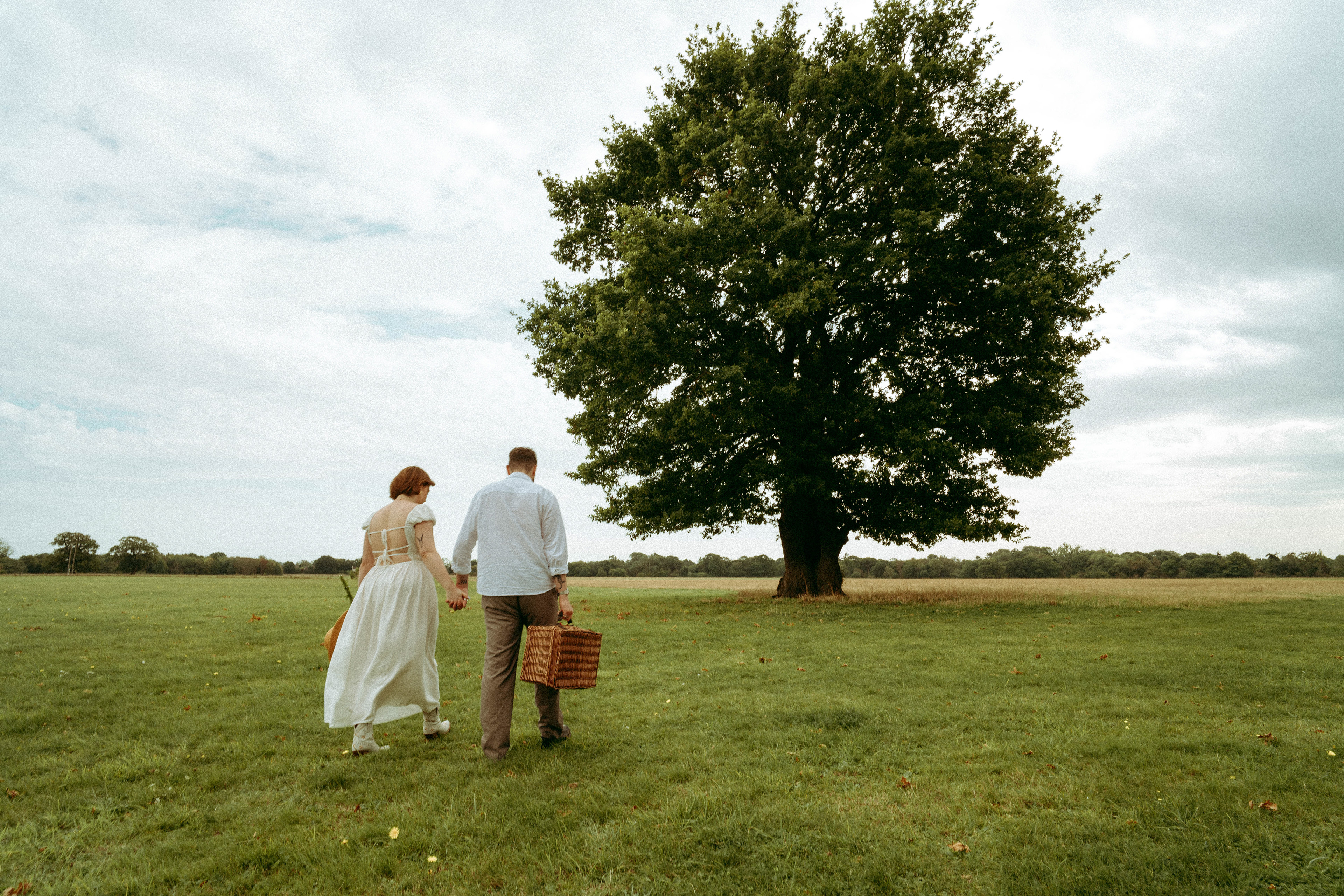 An intimate and playful engagement story set against a grand oak tree. A blend of romantic lifestyle photography and high-end editorial portraits, featuring a curated picnic setting in the Essex countryside.
