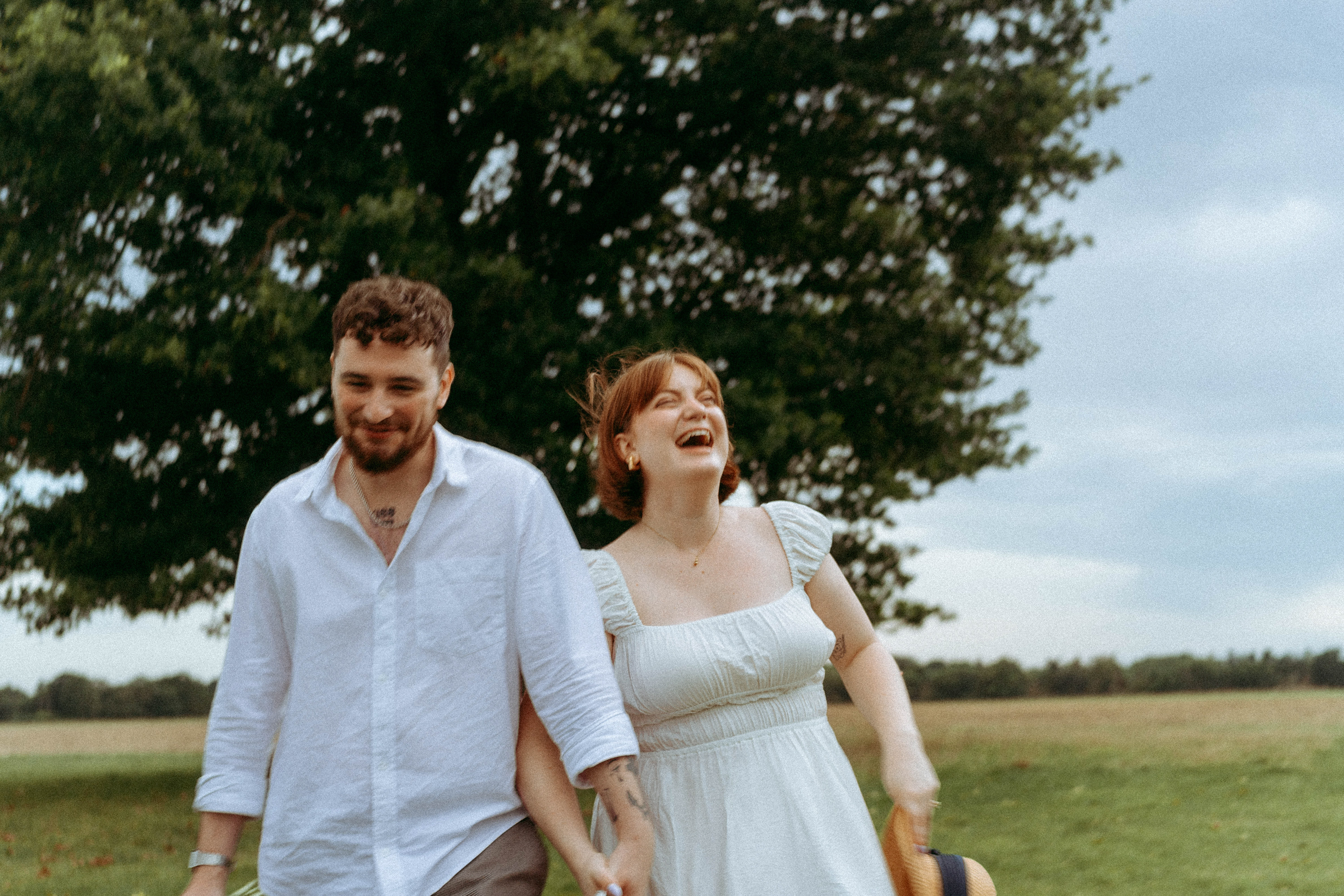 An intimate and playful engagement story set against a grand oak tree. A blend of romantic lifestyle photography and high-end editorial portraits, featuring a curated picnic setting in the Essex countryside.