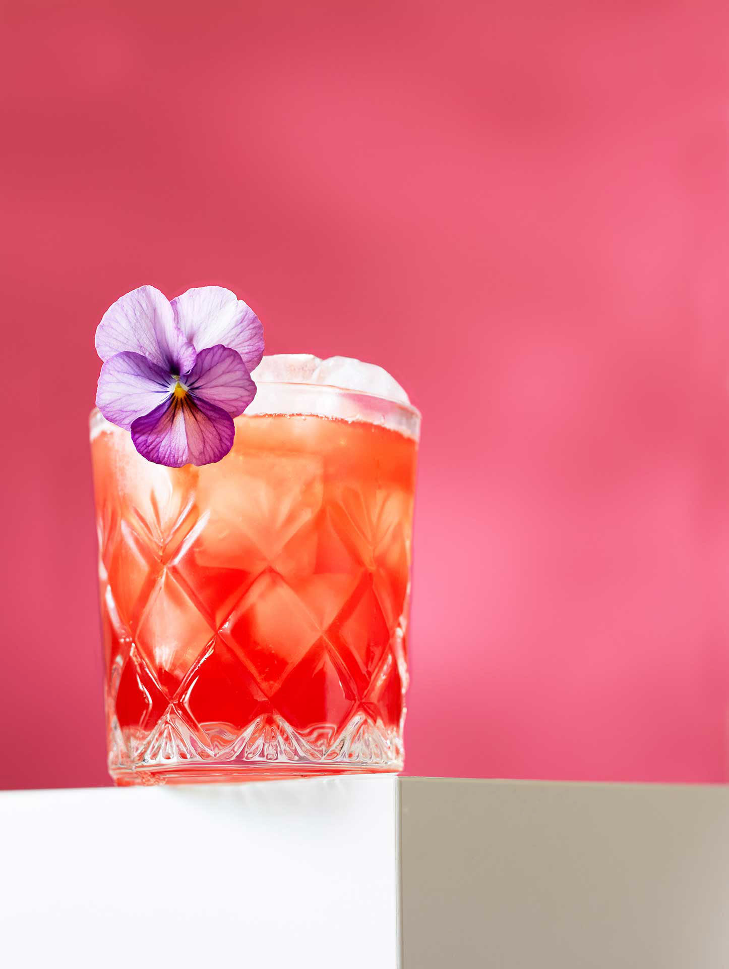 Oranssi cocktail kuvattuna pinkillä taustalla