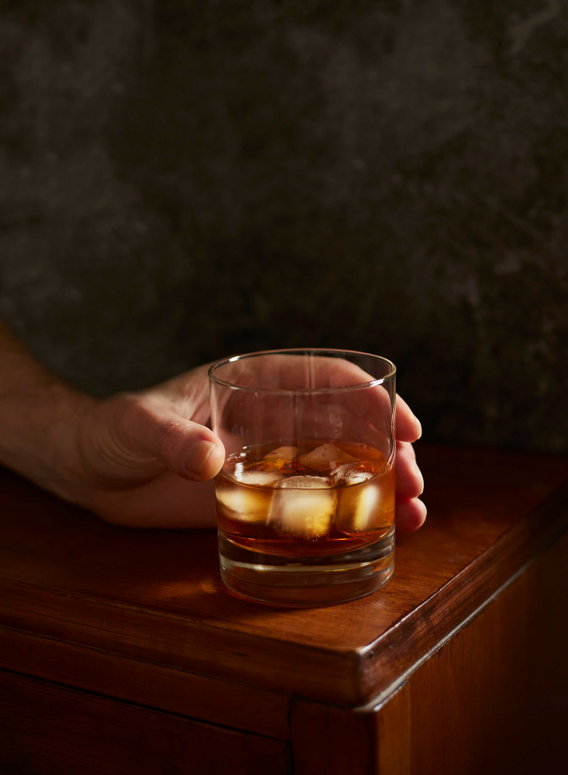 Käsi pitelee viskilasia