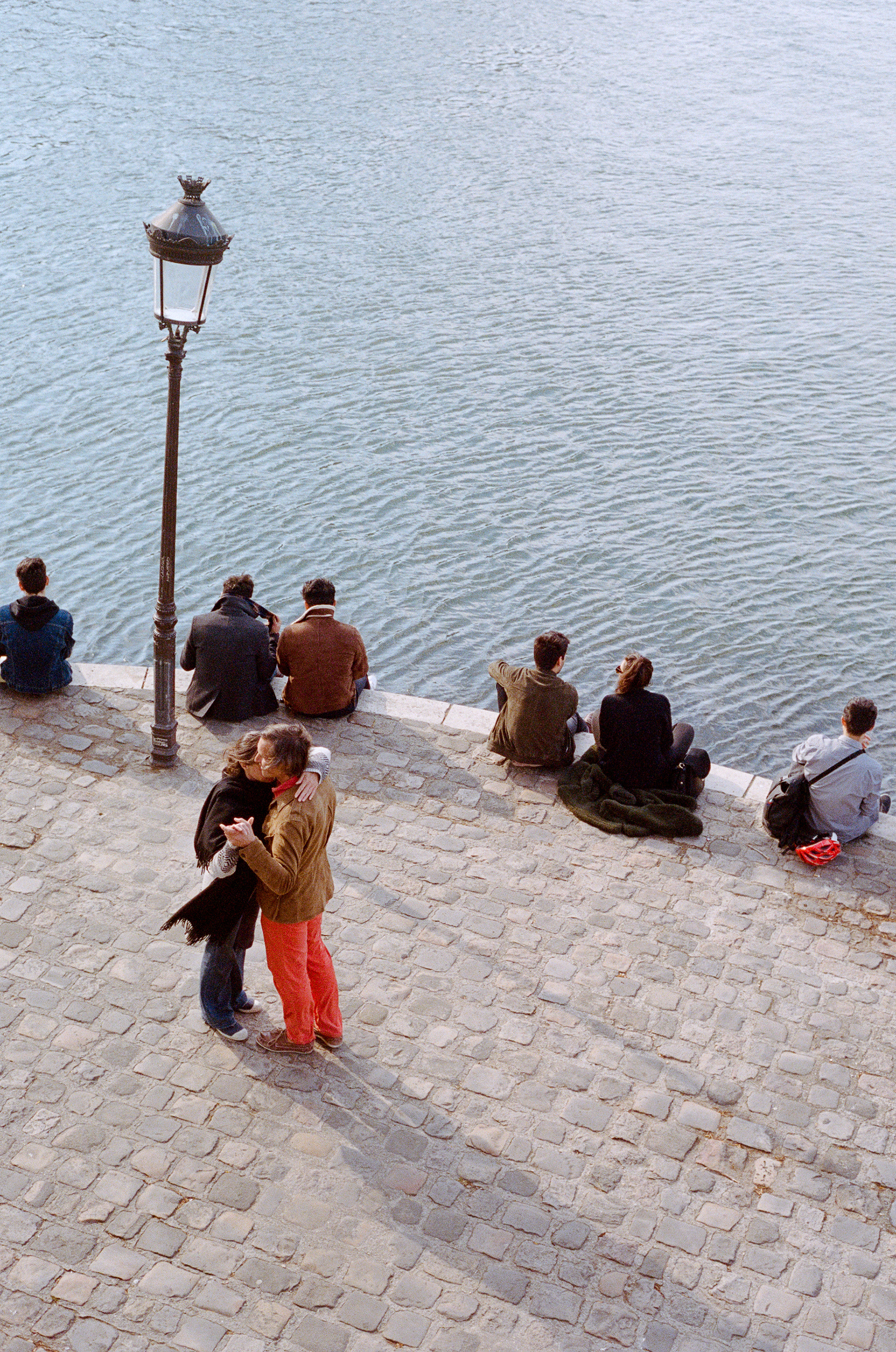 Photographie de rue en couleur illustrant un couple dansant sur les quais parisiens