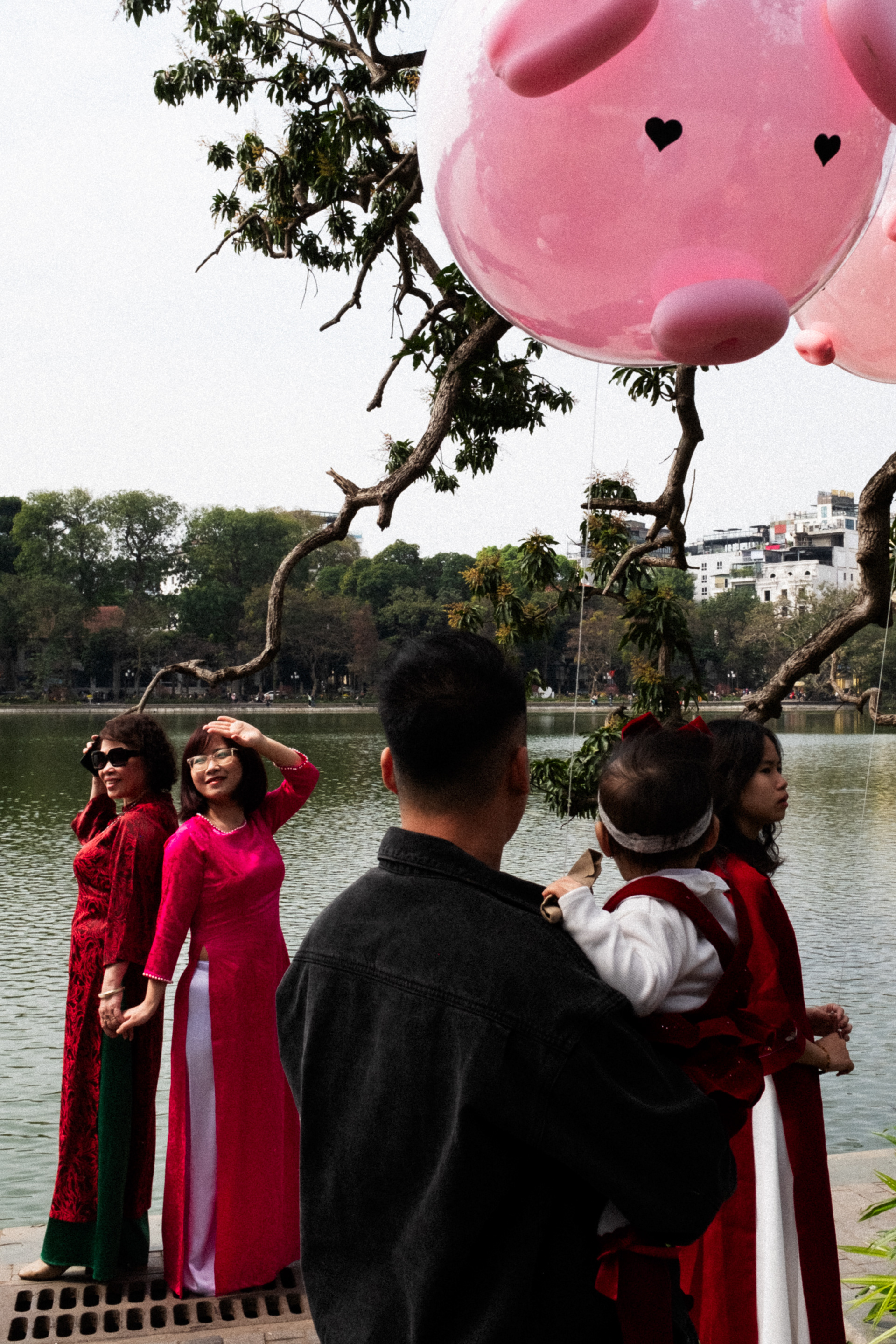 Photographie de rue au Vietnam durant Têt 2024 dans un temple à Hanoï illustrant des femmes se prenant en photo et un enfant tenant un ballon