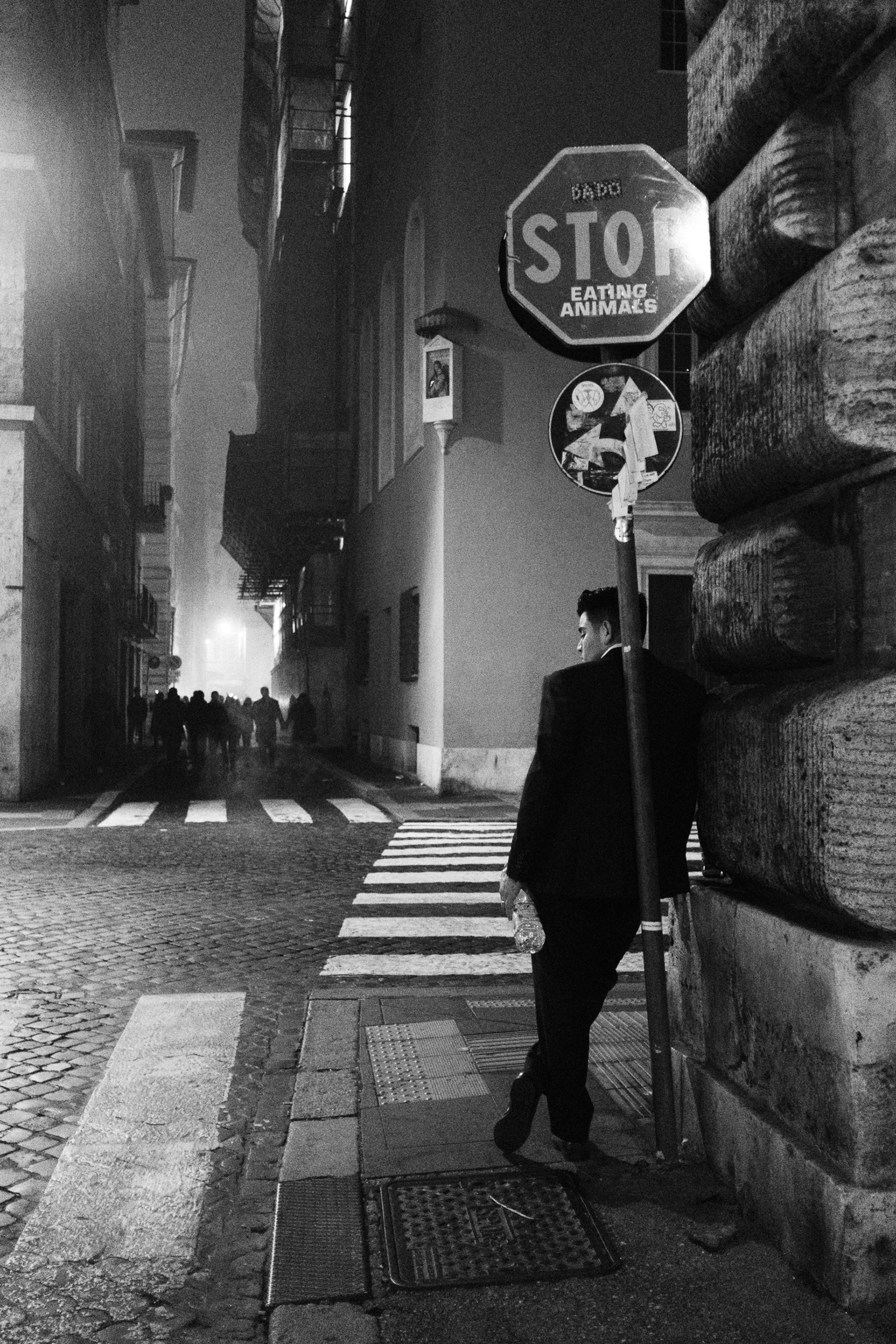 Photographie de rue en noir et blanc prise à Rome durant Nouvel An 2023 illustrant un homme de dos adossé à un mur