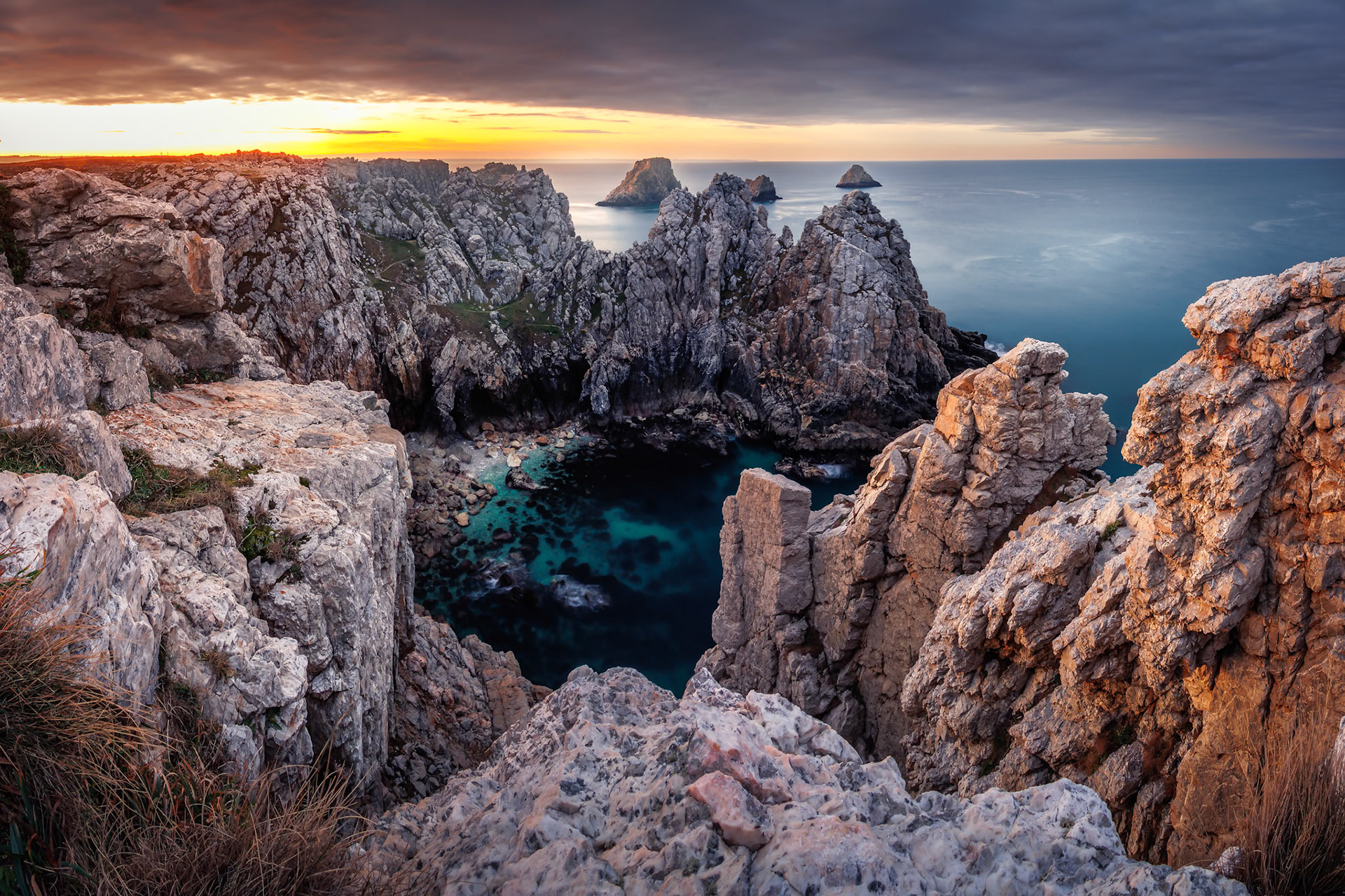 Lever de soleil flamboyant sur la Pointe de Pen-Hir, en Bretagne, entre roche chaude et eau turquoise.