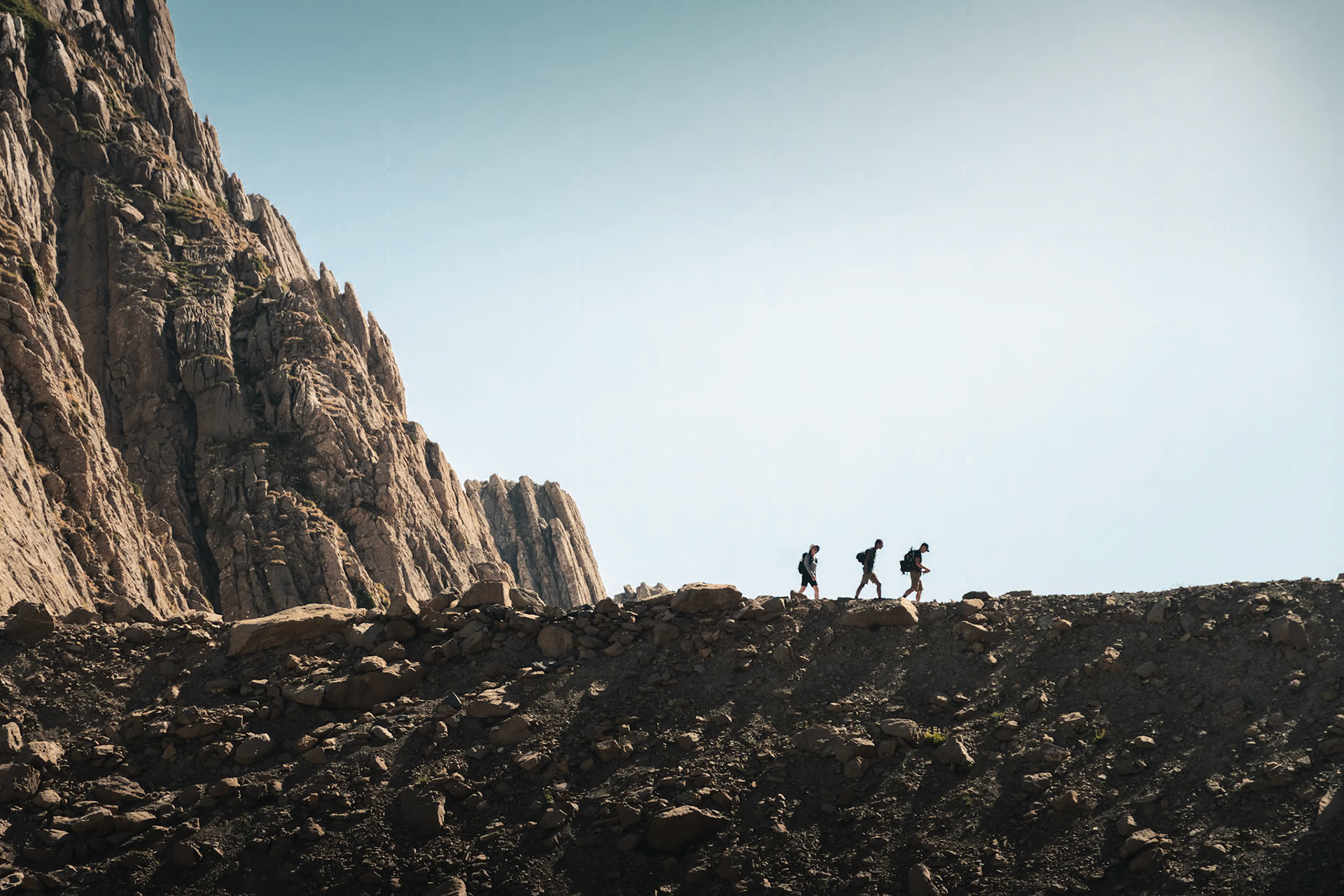 Trois silhouettes sur une arête caillouteuse proche de la Brèche de Roland, en pleine haute montagne.