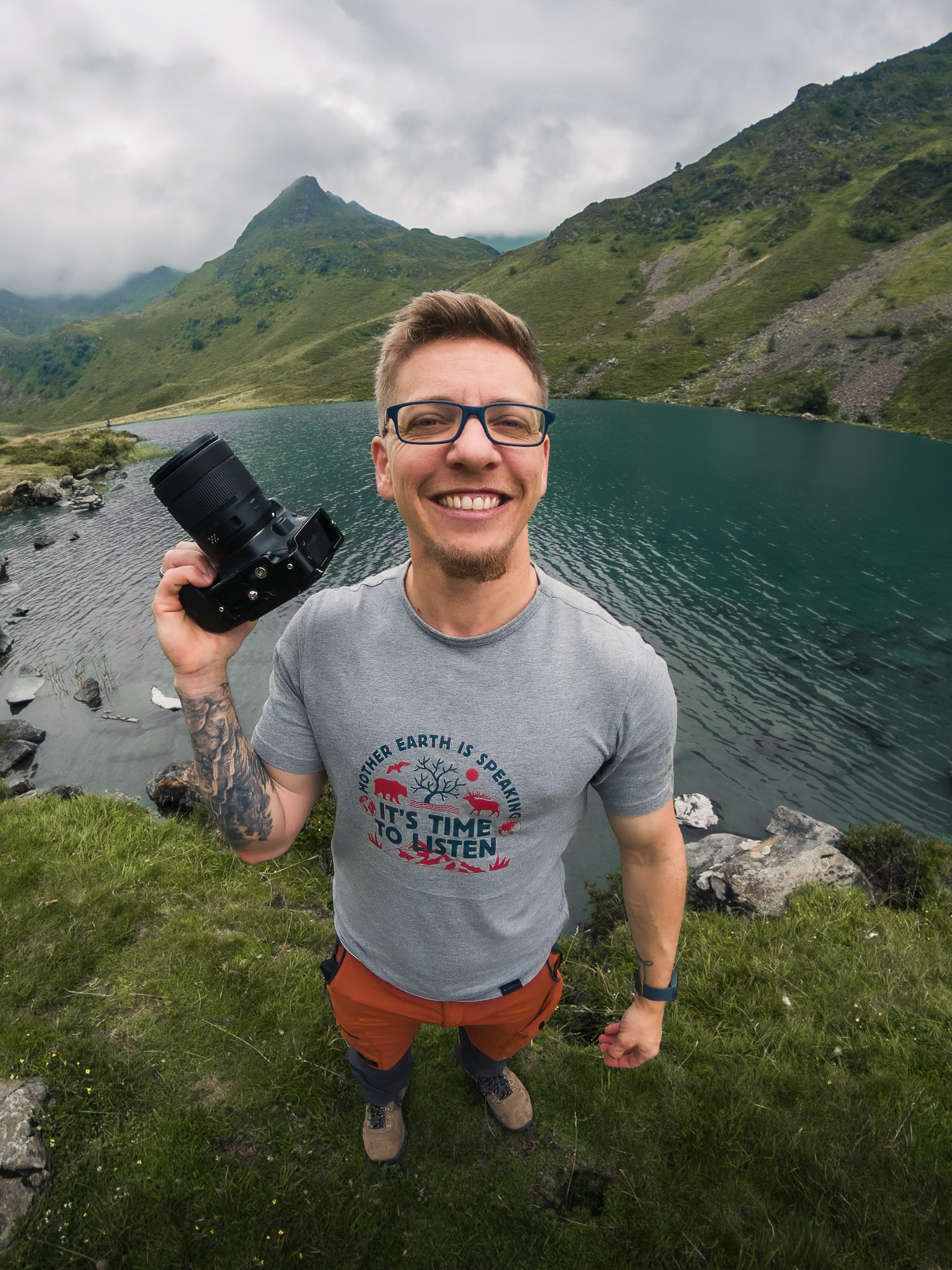 Nathan Ardillon, photographe et vidéaste d'aventure, appareil photo à la main, devant le lac d'Isaby à Hautacam dans les Hautes-Pyrénées.