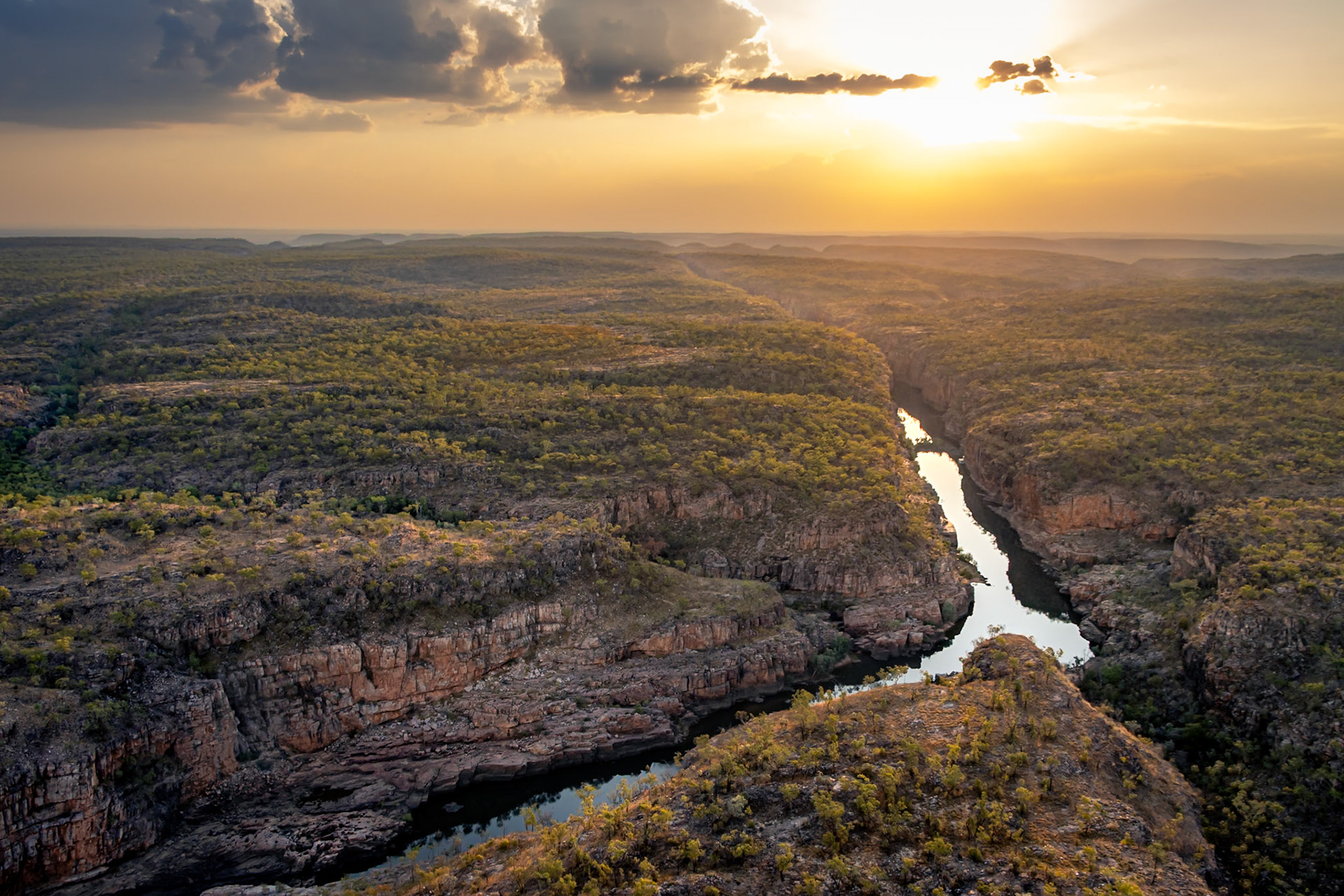 Vue aérienne depuis un hélicoptère au coucher du soleil sur les gorges de Katherine, dans le Nitmiluk National Park en Australie — une rivière serpente entre des falaises abruptes sous un ciel embrasé