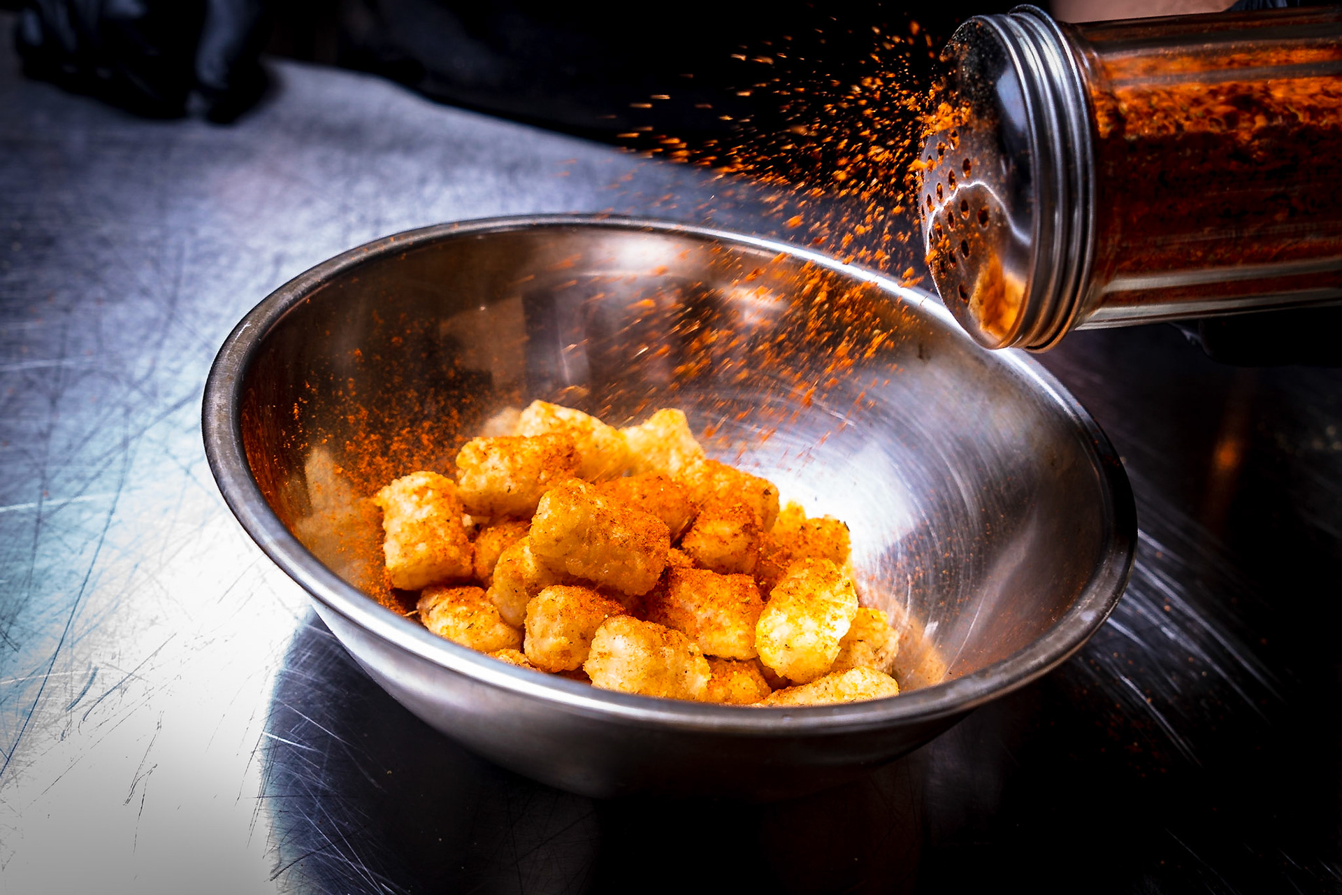peri peri dust shaking onto tater tots.