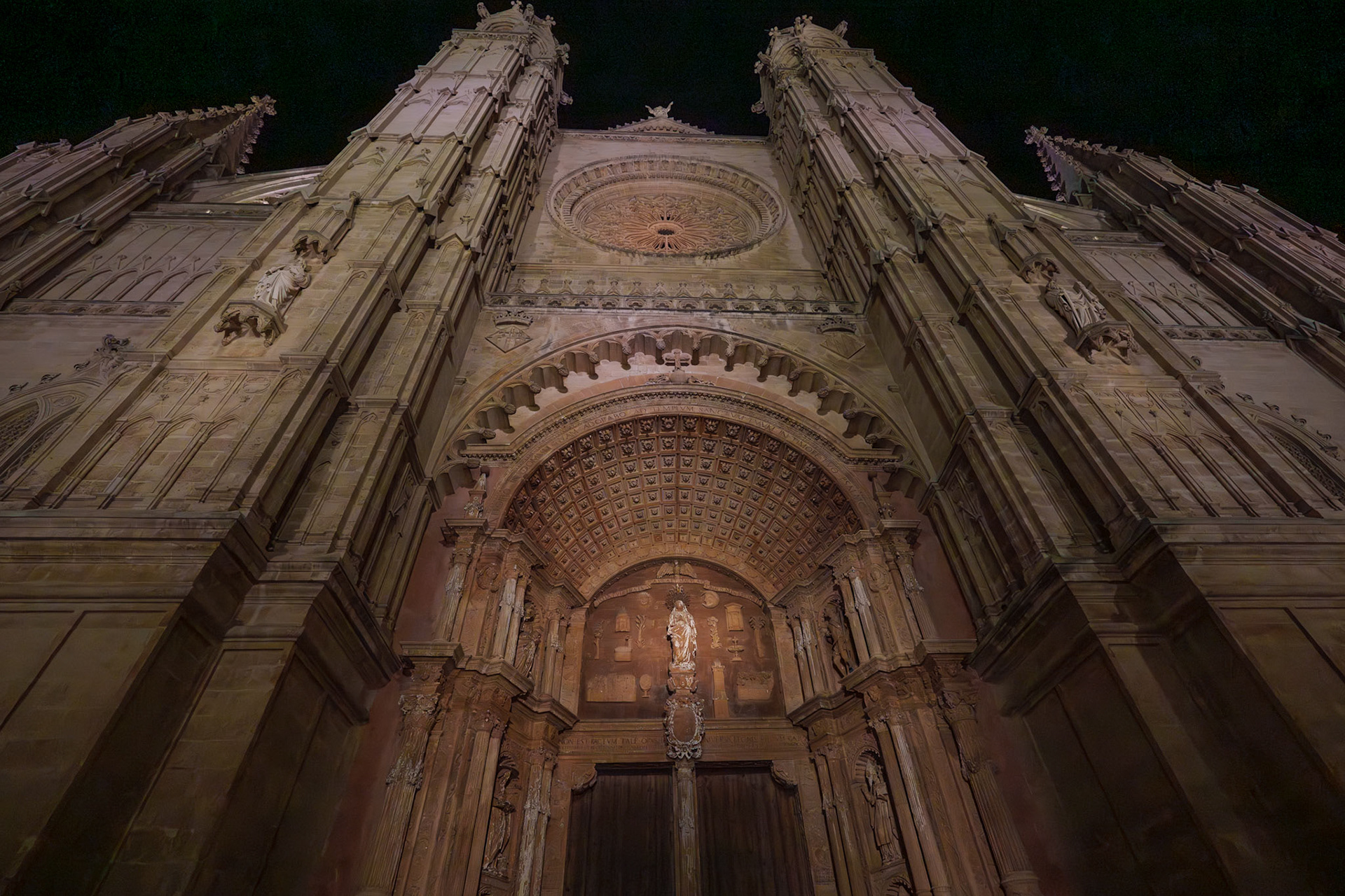 the cathedral of palma de mallorca, la seu, stands under the night sky, its gothic facade a tapestry of stone. light washes over its intricate sculptures and soaring spires, a beacon in the dark. this historic landmark, a crown of the city, gazes out over the mediterranean, a sentinel of faith and beauty. la seu, a gothic masterpiece, was built on the site of a former mosque. construction began in the 13th century and continued for centuries, allowing a mix of styles to influence its design. its rose window is one of the world's largest, flooding the interior with a kaleidoscope of light at dawn. its presence is a testament to mallorca's rich history, intertwining the sacred with daily life and standing as a symbol of the island's resilience and artistic spirit.