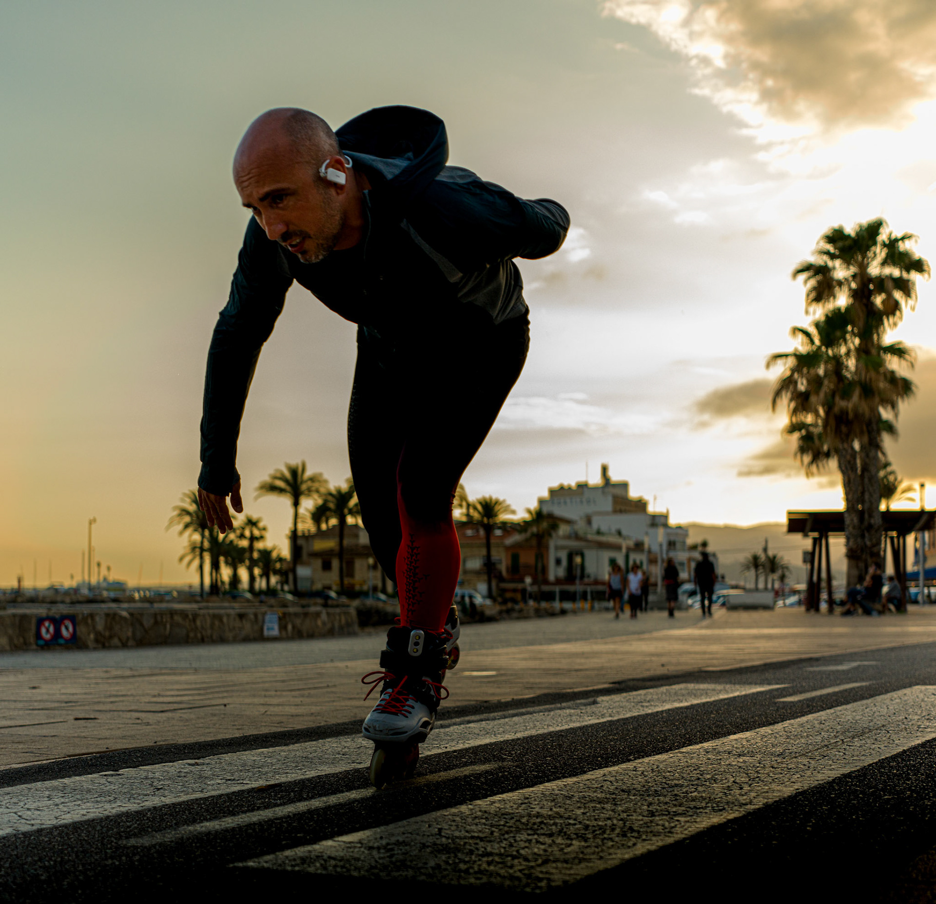 as the sun dips low over portixol, casting a warm, golden glow, a solitary skater glides with effortless grace along the promenade. the stillness of the approaching evening envelops the scene, punctuated only by the rhythmic sound of wheels against the pavement. shadows stretch long, merging with the fleeting light, capturing a moment suspended between day and night. in the background, palm trees stand as silent sentinels, framing the tranquil beauty of a community winding down, where movement meets serenity in the heart of palma de mallorca.