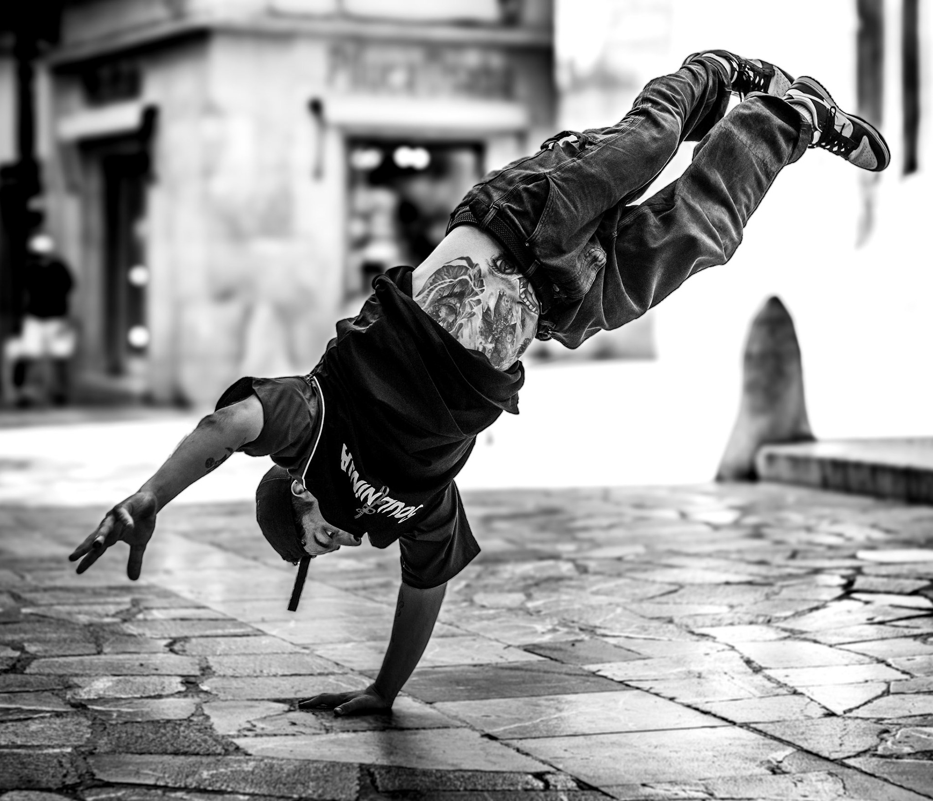 in the heart of palma's old town, the streets come alive with the raw energy of soulninjas, a local breakdance crew. the dancer's form is frozen in mid-air, defying gravity with effortless skill. every detail, from his tattoo to the precise handstand, speaks of years of dedication and passion. the monochrome tones strip the scene back to its essence—movement, strength, and expression.