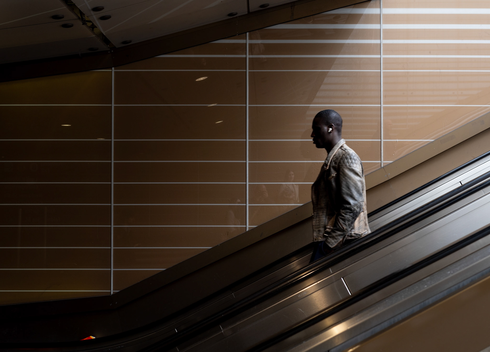 descending into the rhythm of munich's underground, a solitary traveler rides the escalator at karlsplatz station. His profile cuts a thoughtful figure against the modern lines and muted tones of the subway’s architecture. It's a brief moment of stillness in the flow of urban movement, a snapshot where personal journey meets public transit.